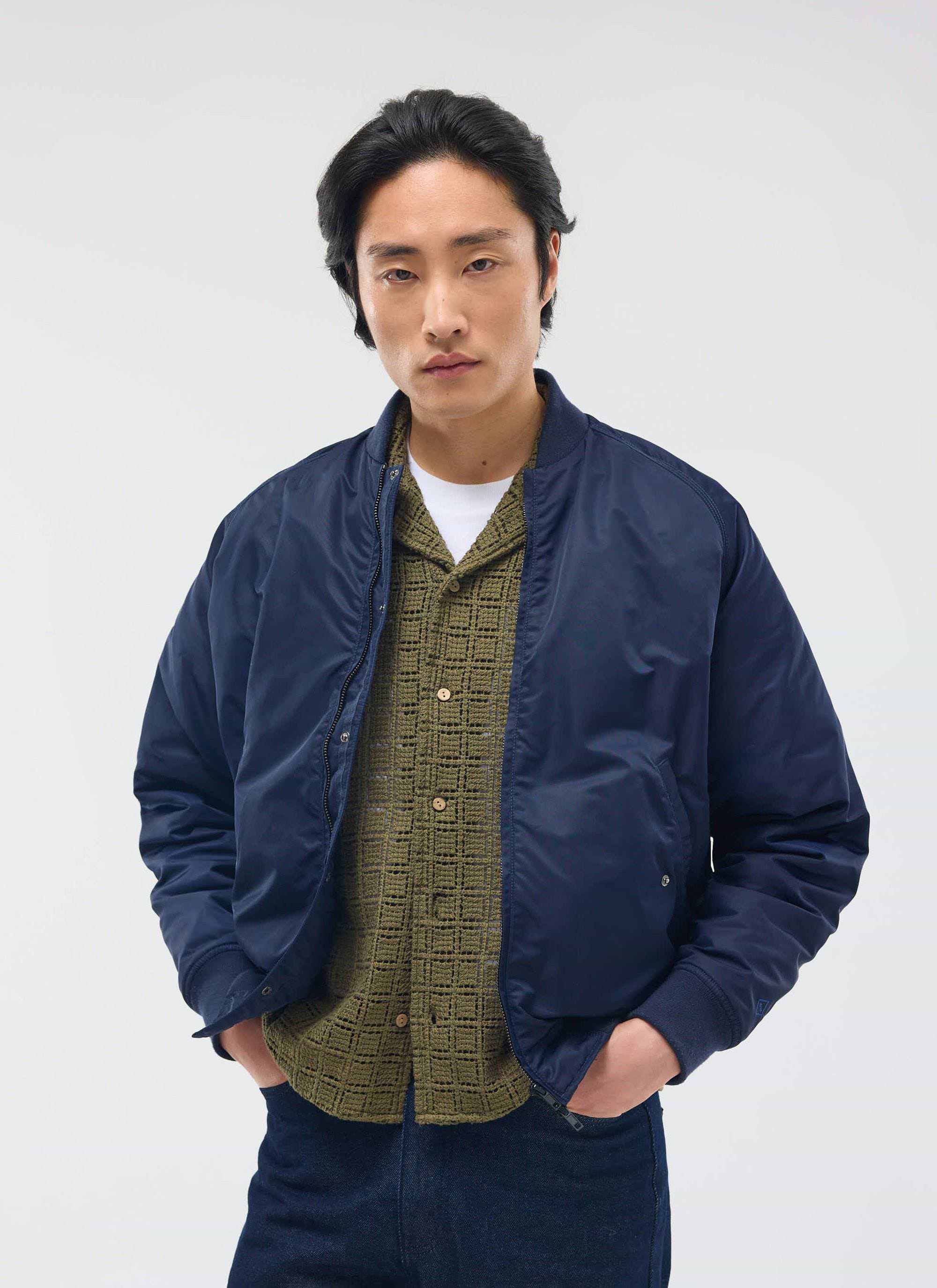 A model wears the Percival Palermo Crochet Cuban Shirt in olive green, layered under a navy bomber jacket.