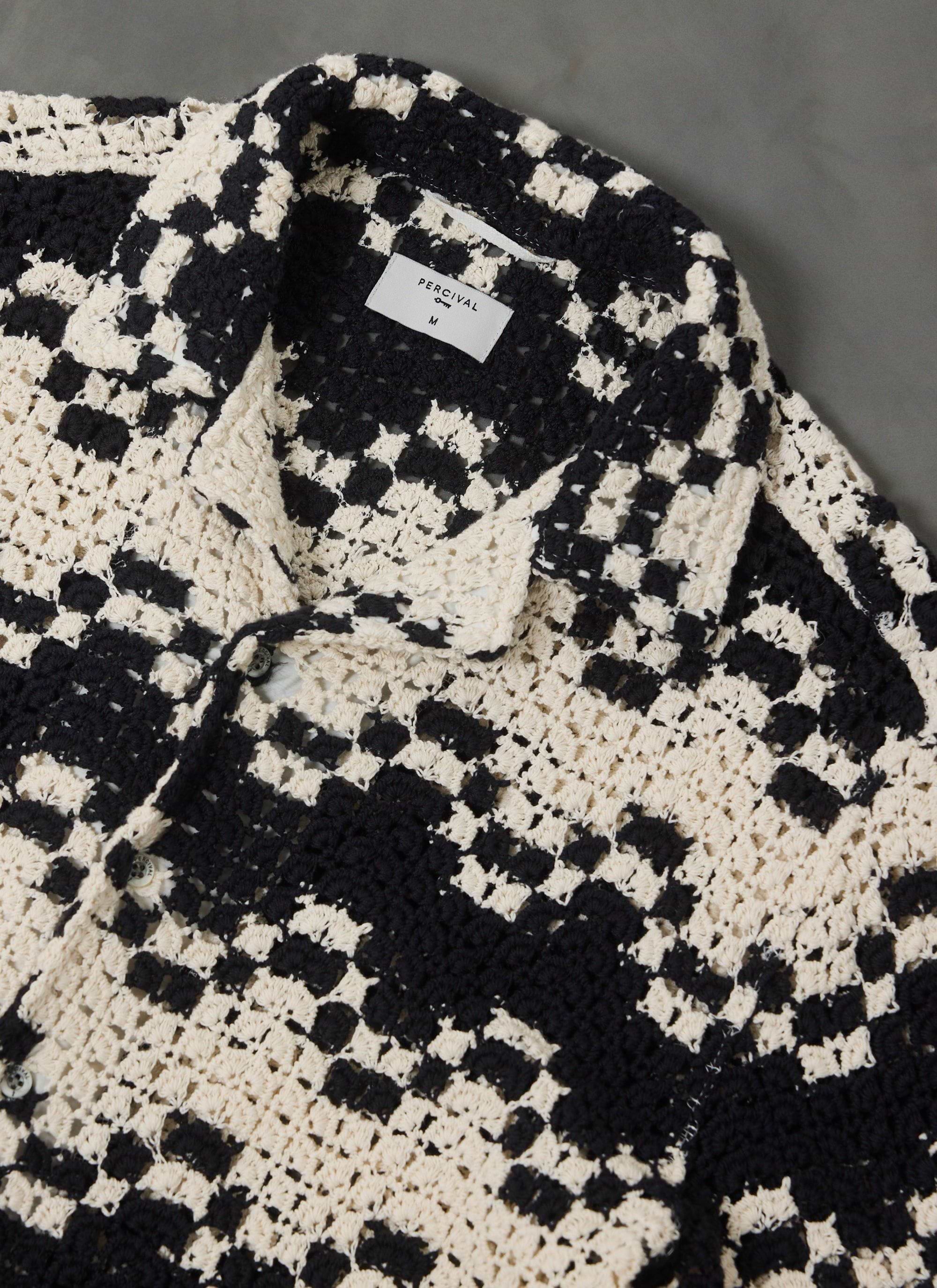 A close-up flat lay of the Percival Naples Crochet Cuban Shirt, detailing the black and ecru checkered knit and collar.