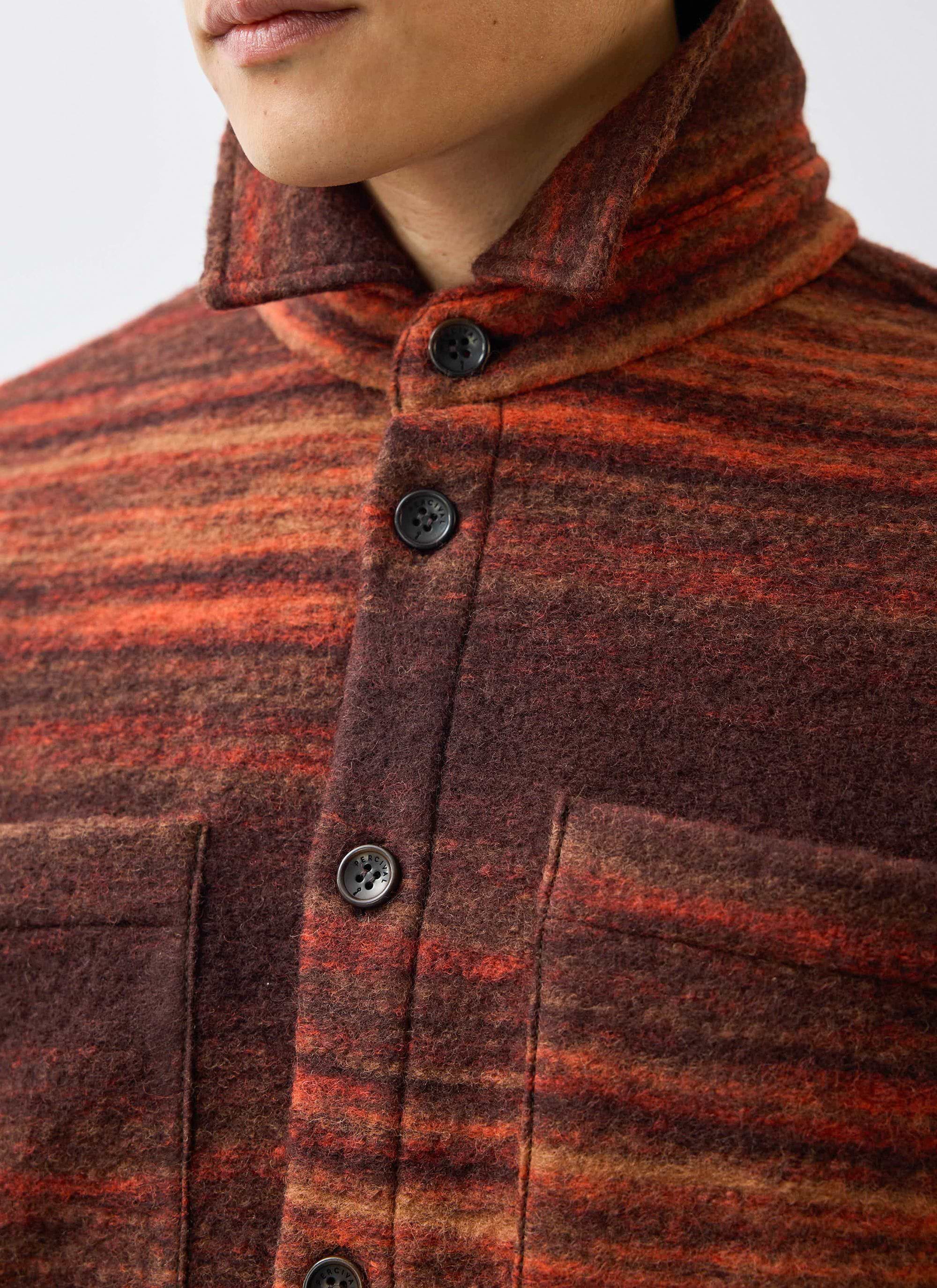 A close-up of the Percival Mississippi Jacquard Overshirt, showing the burnt orange boiled wool texture and branded buttons.