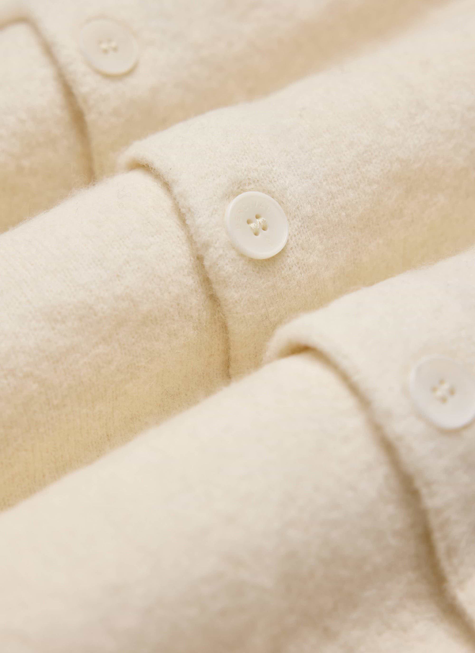 Close up of the Percival Archive Wool Knitted Cardigan in ecru, showing the soft texture and button details.