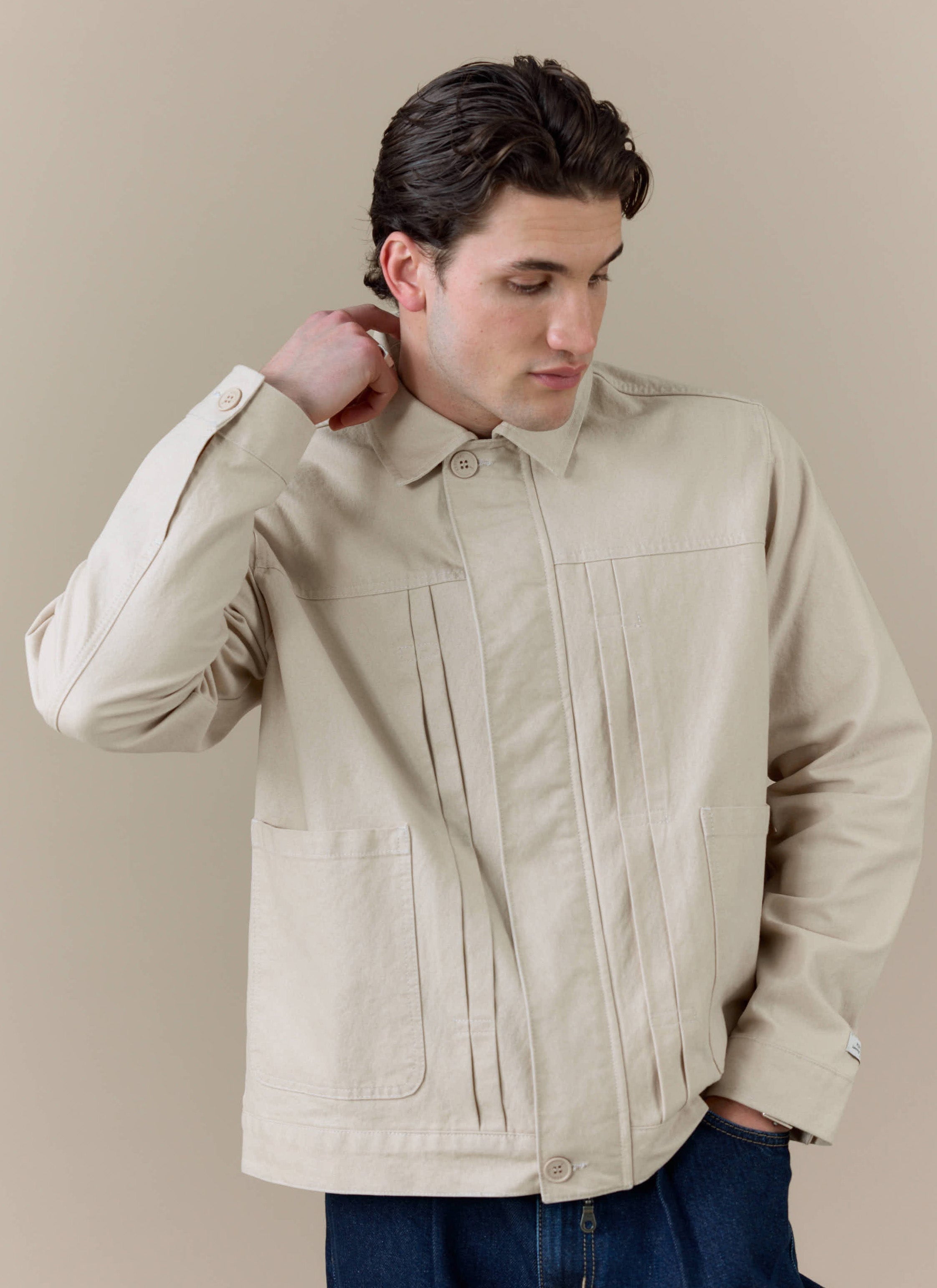 Model wearing the cream Ernst Jacket by Percival, featuring a double pleated front and structured, boxy fit.