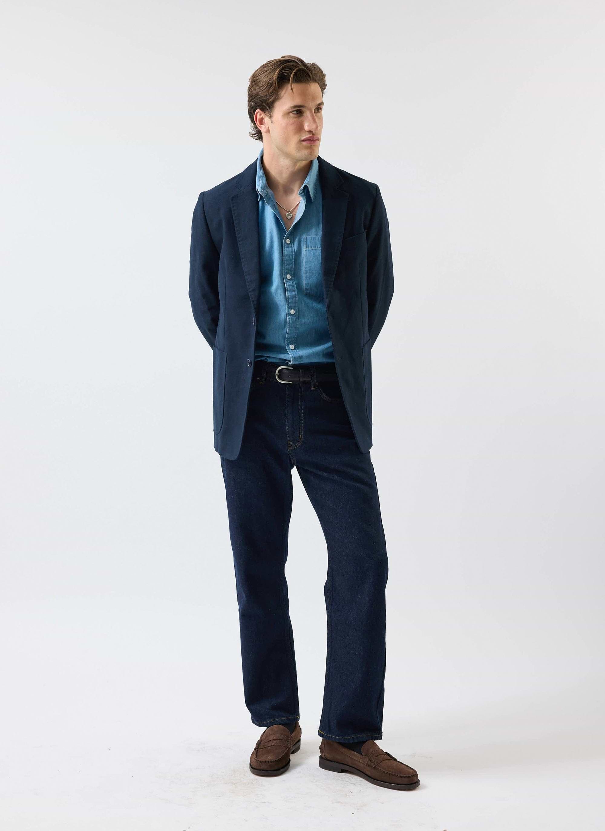 A model wears the Percival Marco Pearce light wash denim shirt, styled under a navy blazer with dark jeans.
