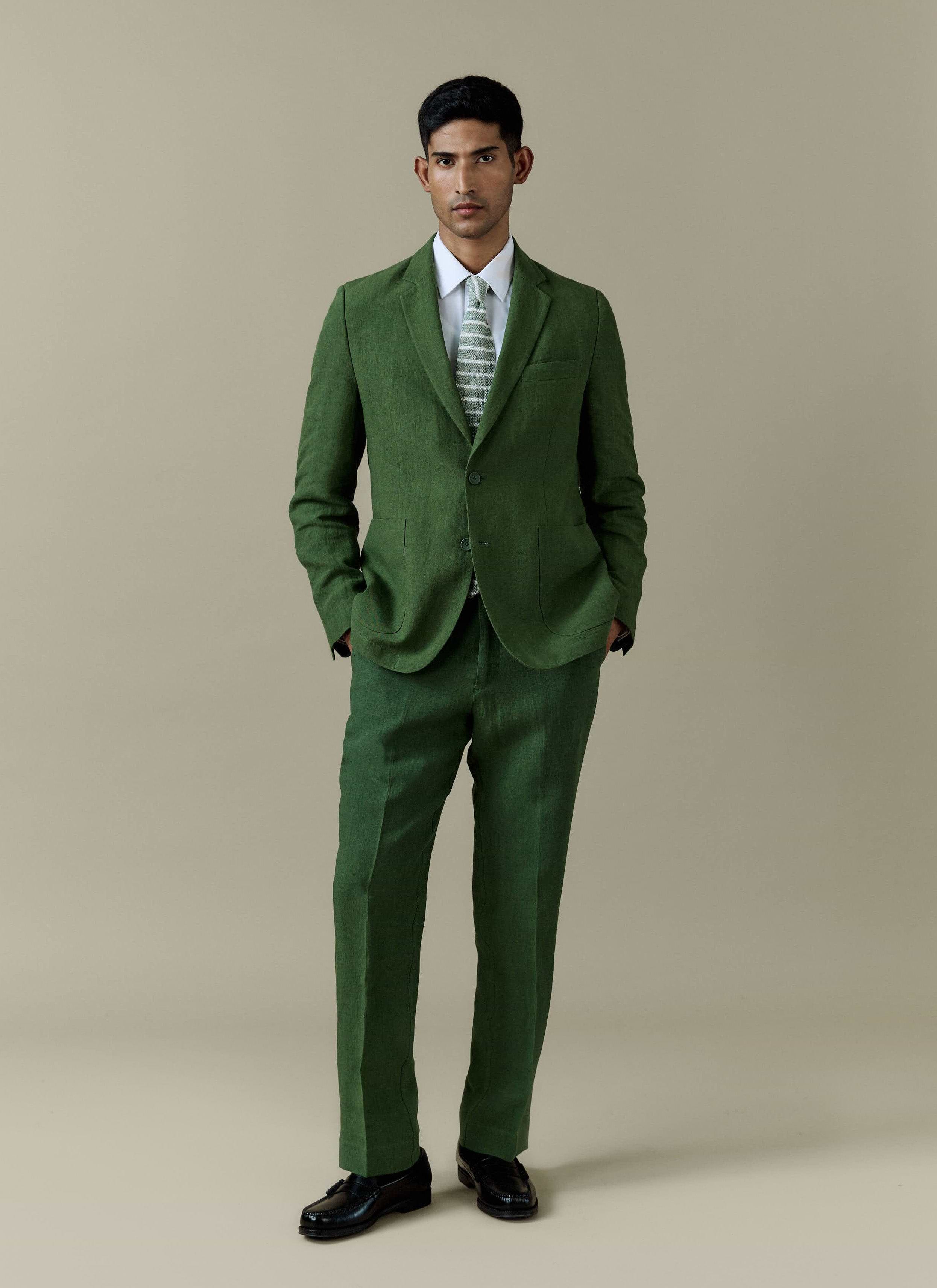 Forest green Percival tailored linen blazer and matching suit trousers, styled with a white shirt and patterned tie.