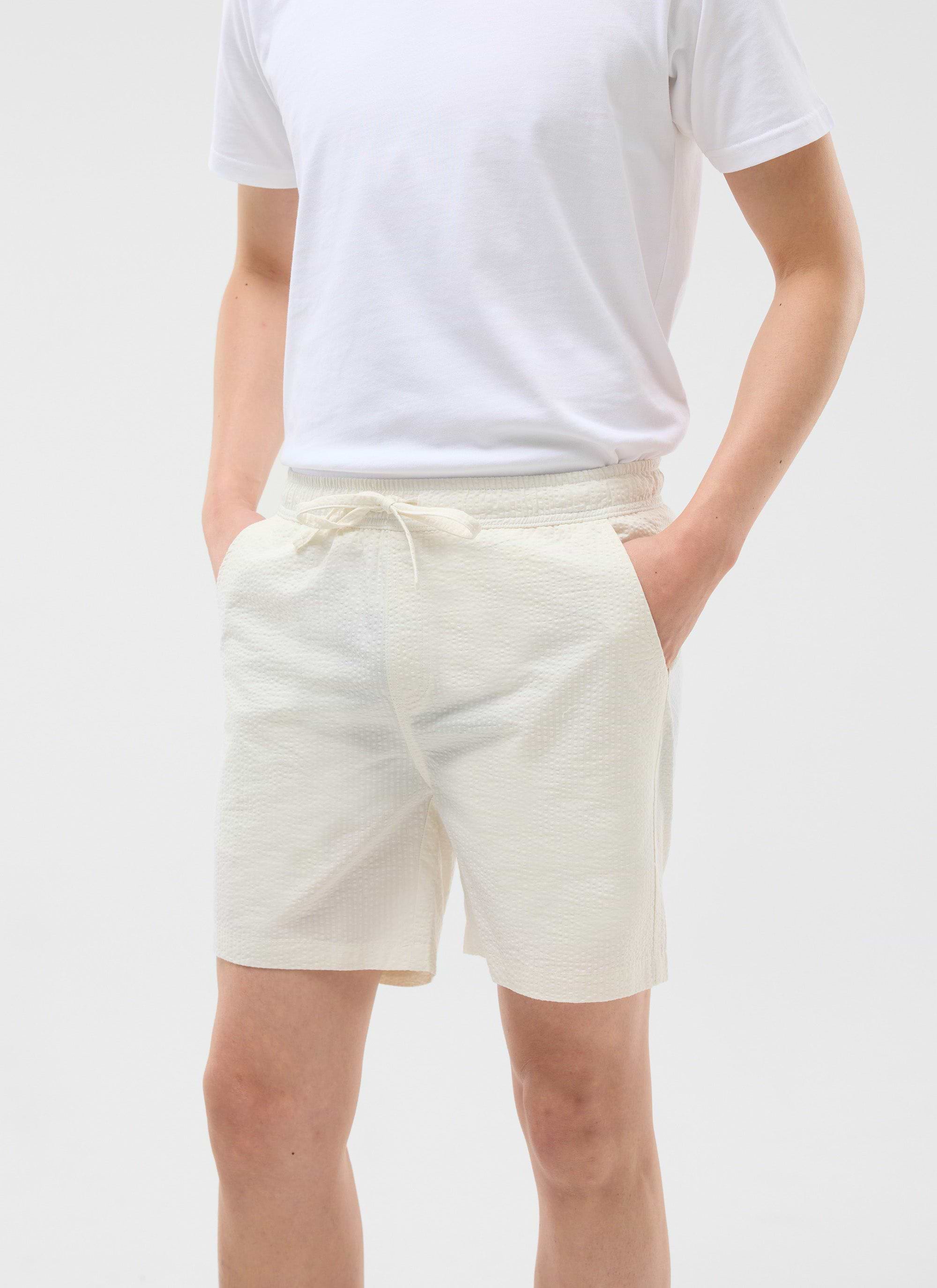 A model wears the cream Percival Classic Shorts in a seersucker fabric, styled with a simple white t-shirt.