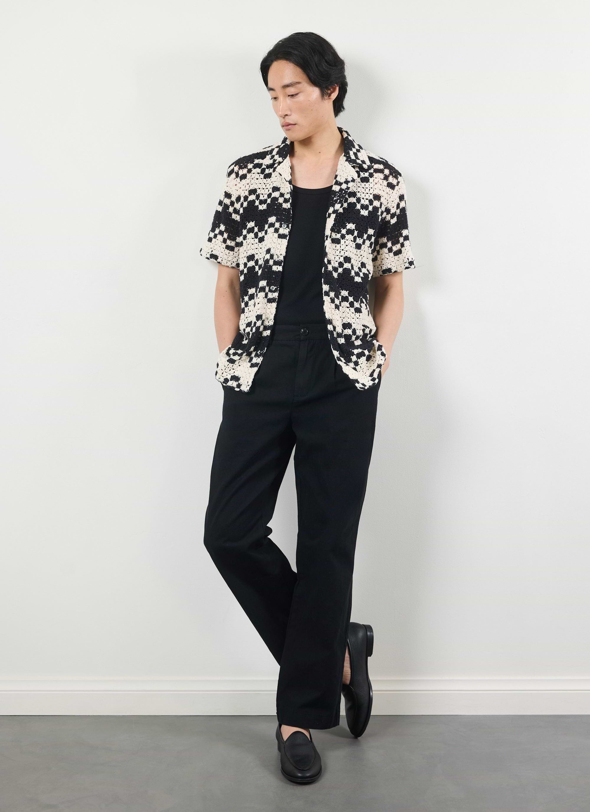 A model wears the Percival Naples Crochet Cuban Shirt in ecru, styled open over a black top and trousers.