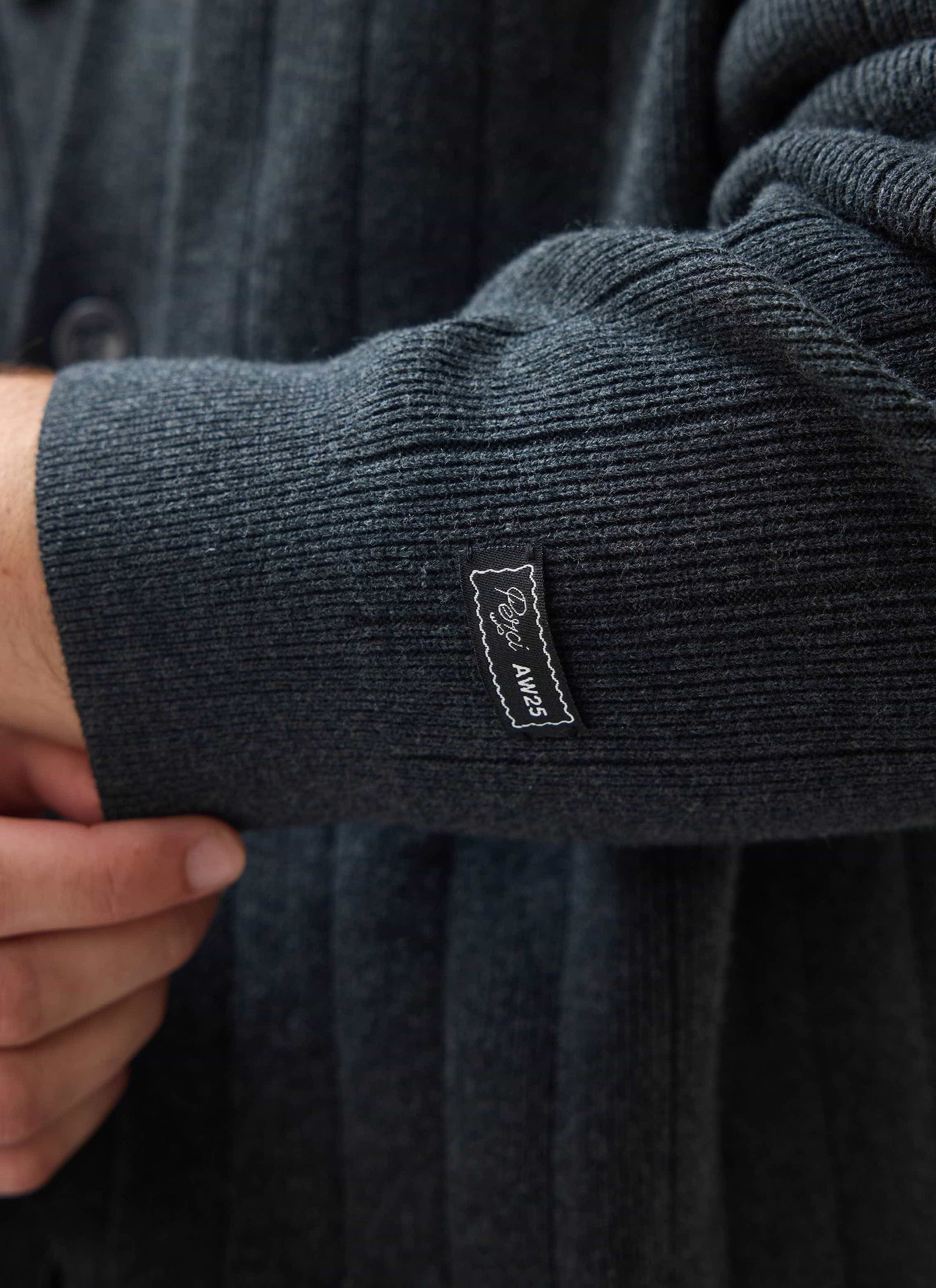 A close-up of the ribbed cuff on the grey wool-blend Editor Cardigan from Percival, showing the small black brand label.