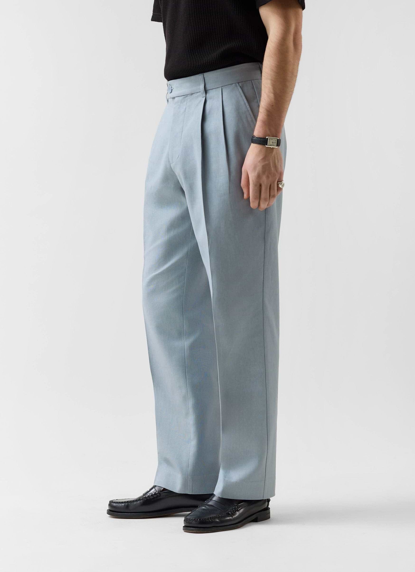 Model wearing Percival's light blue linen pleated tailored trousers with a black top and loafers.