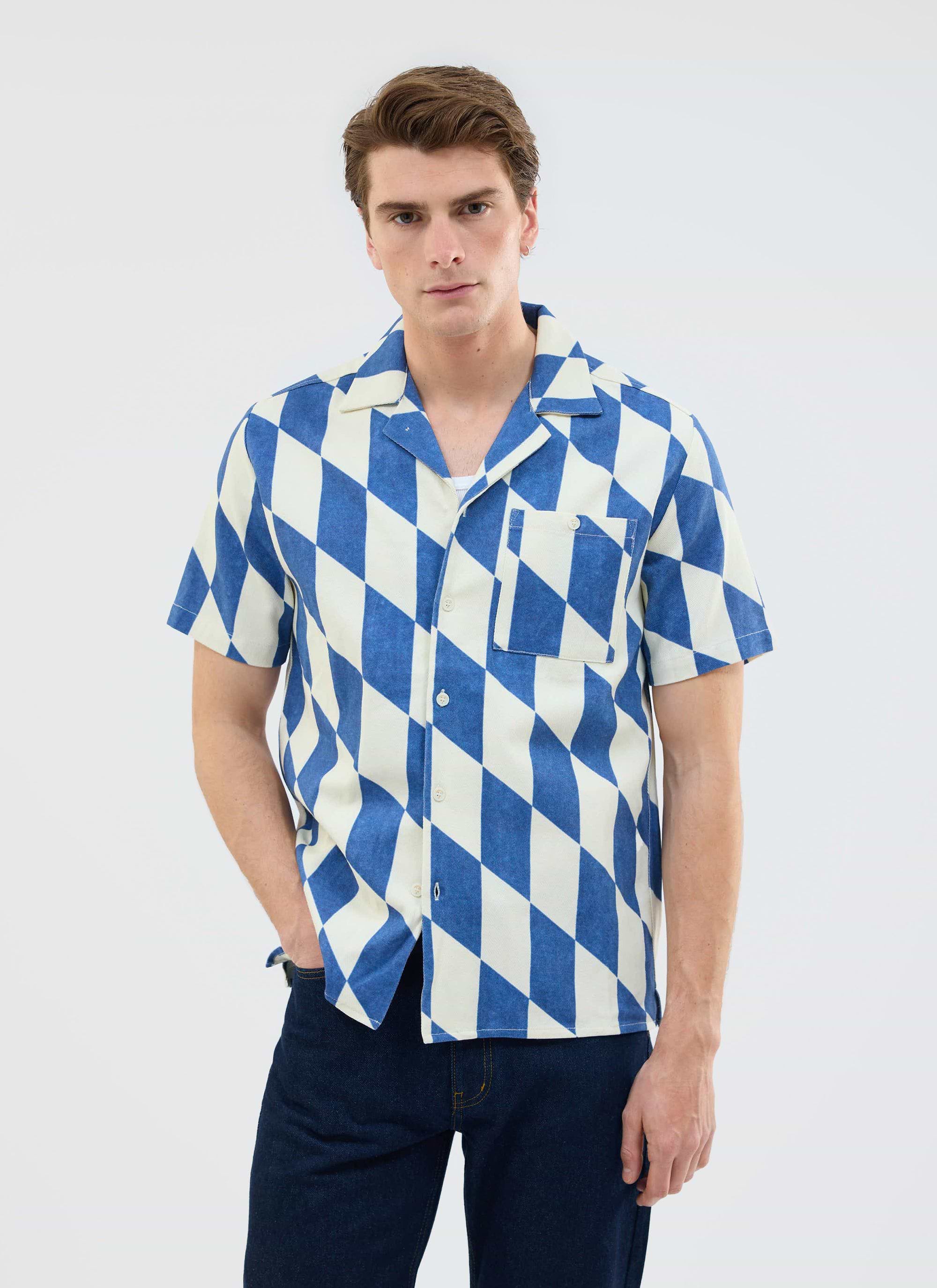 A male model wears the Percival Market Diamond Cuban Shirt, a short sleeve shirt in an ecru and navy diamond print.
