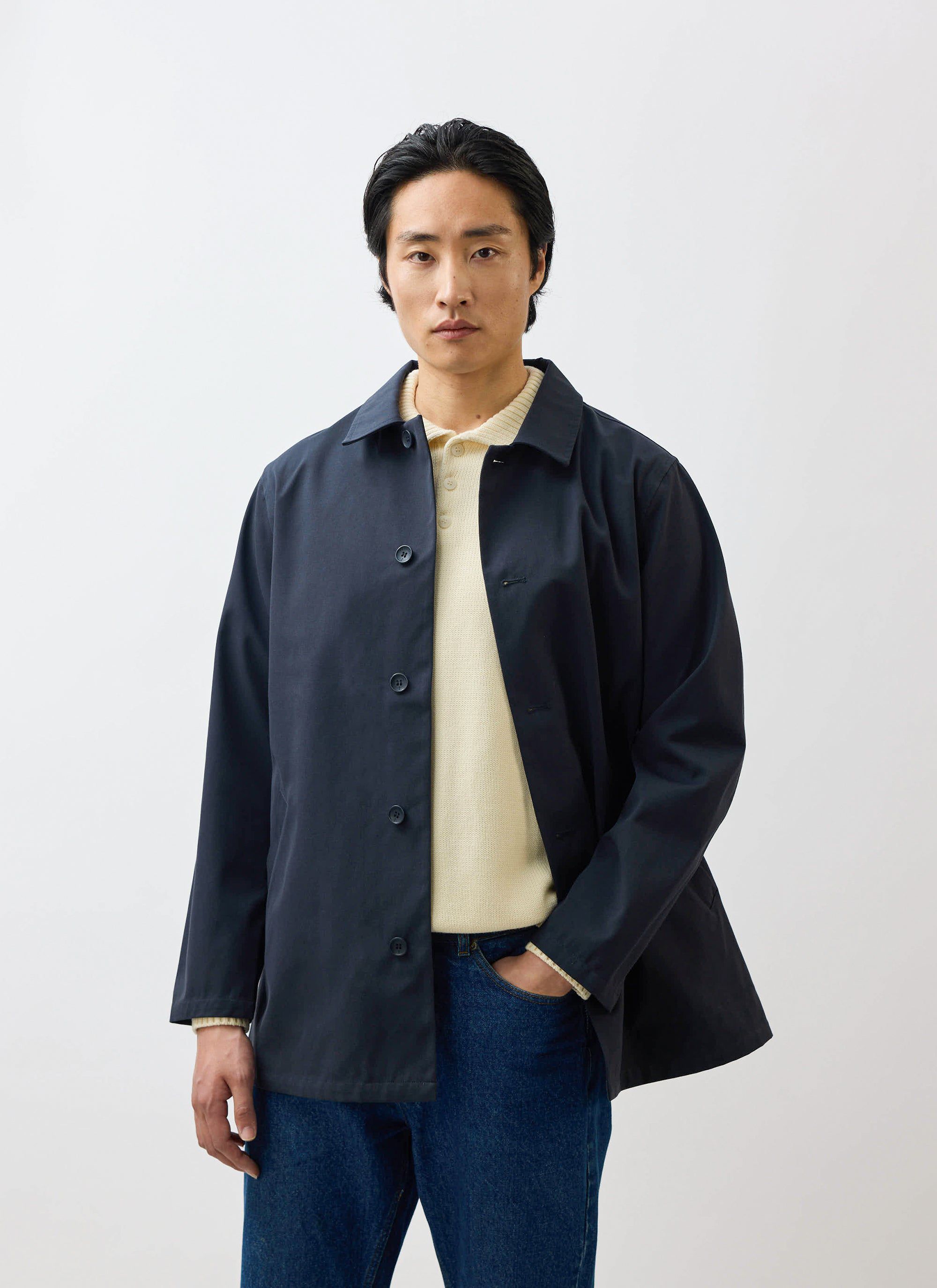 A model wearing the waterproof Percival Sherlock Short Trench Coat in midnight, styled with a cream knit and blue jeans.