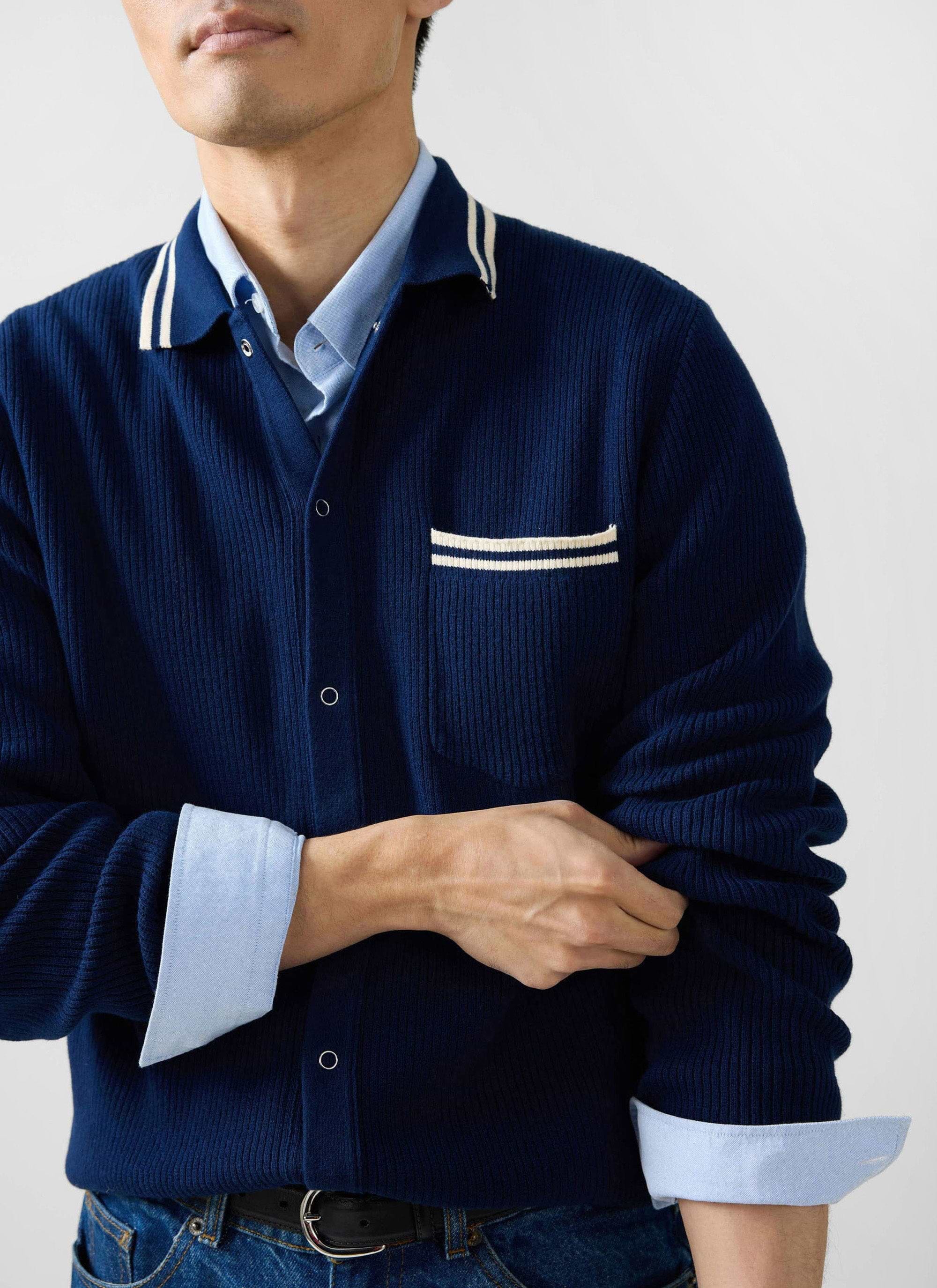 A close-up of a model wearing the Percival Pablo Cotton Knitted Shirt in navy, layered over a light blue collared shirt.