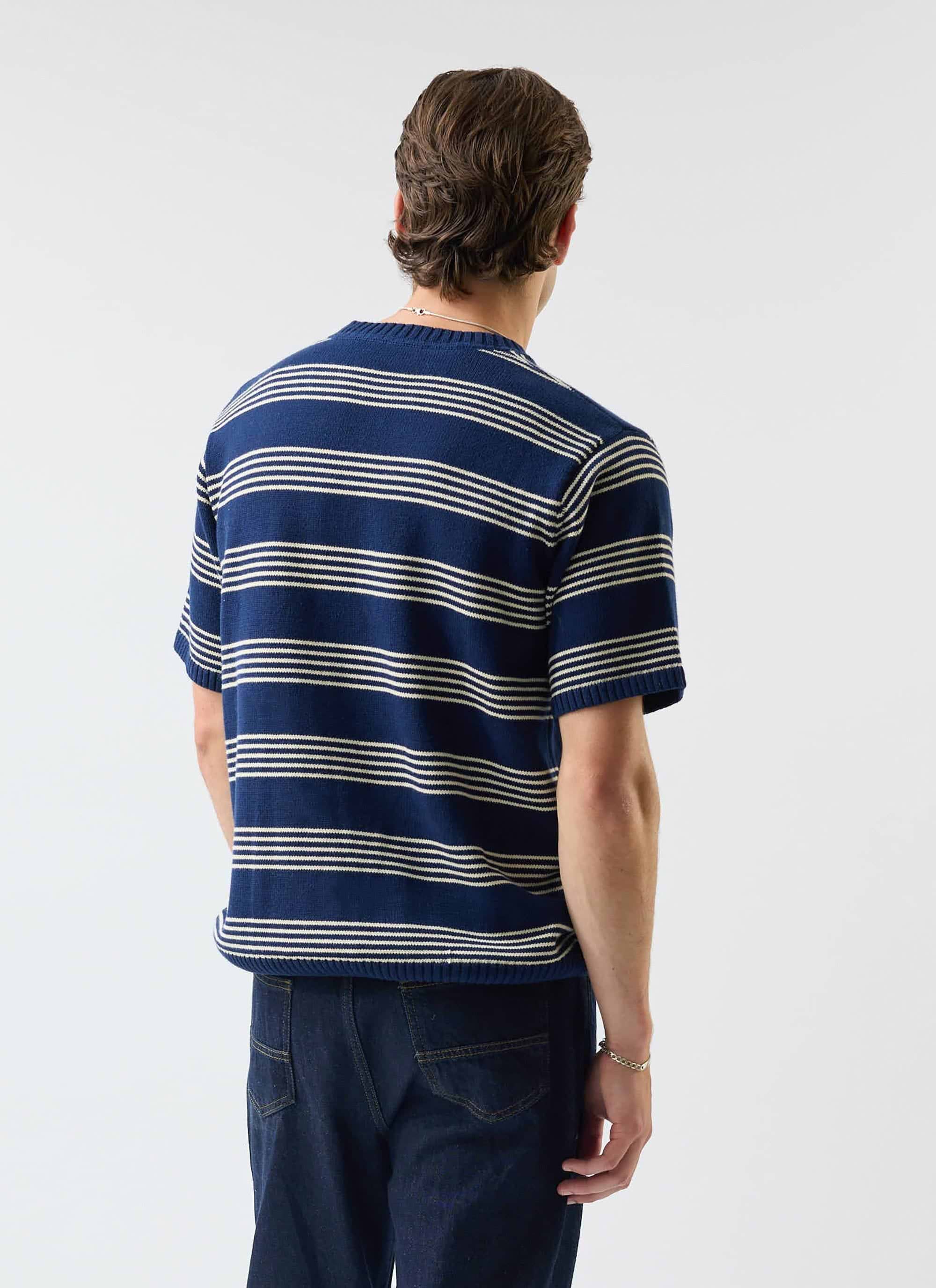 The back of the Percival Fiction Striped Knitted T Shirt in navy, as worn by a model with dark denim jeans.