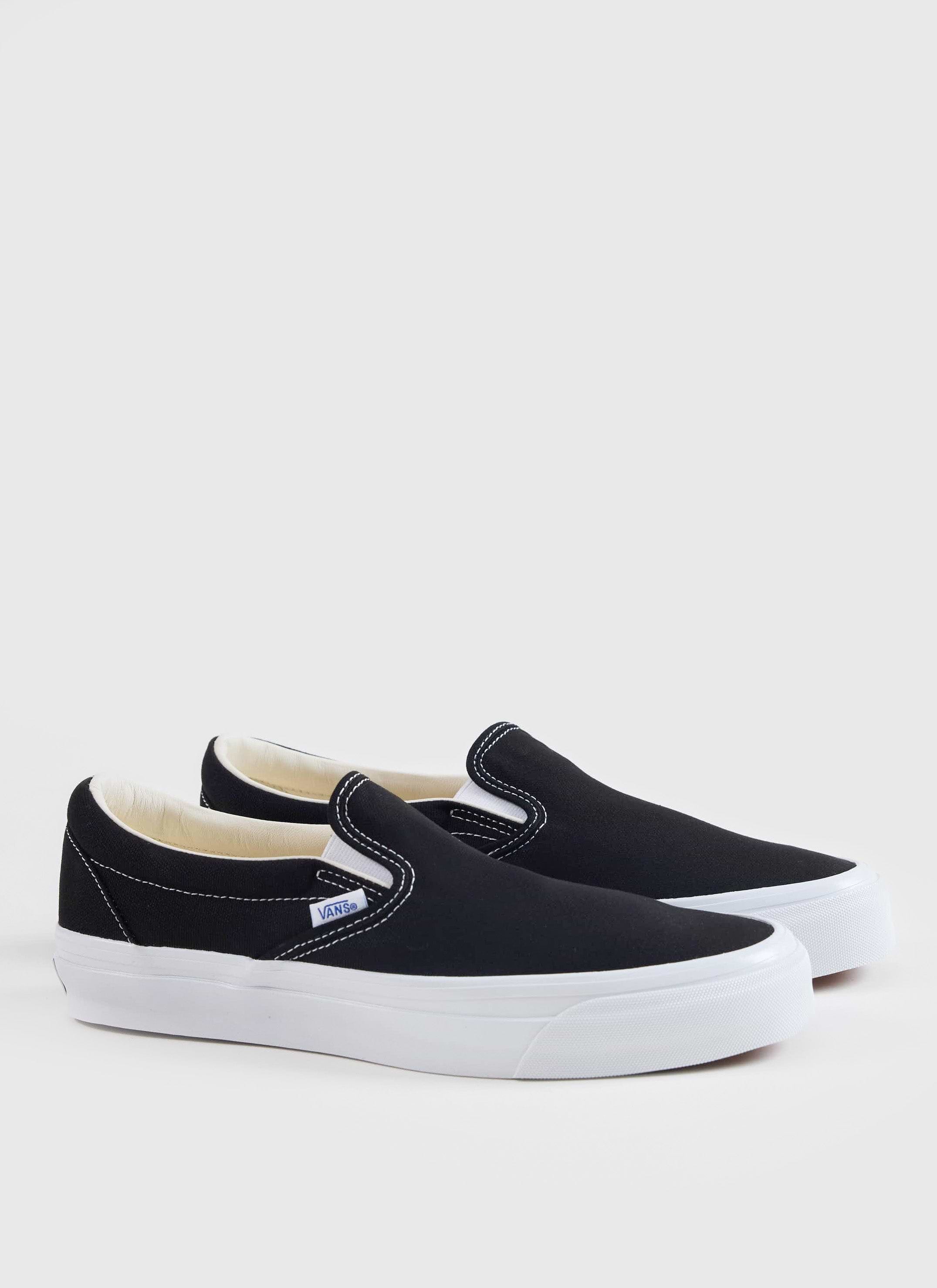 Black Vans Slip-On Reissue 98 shoes with white soles and contrast stitching, available from Percival.
