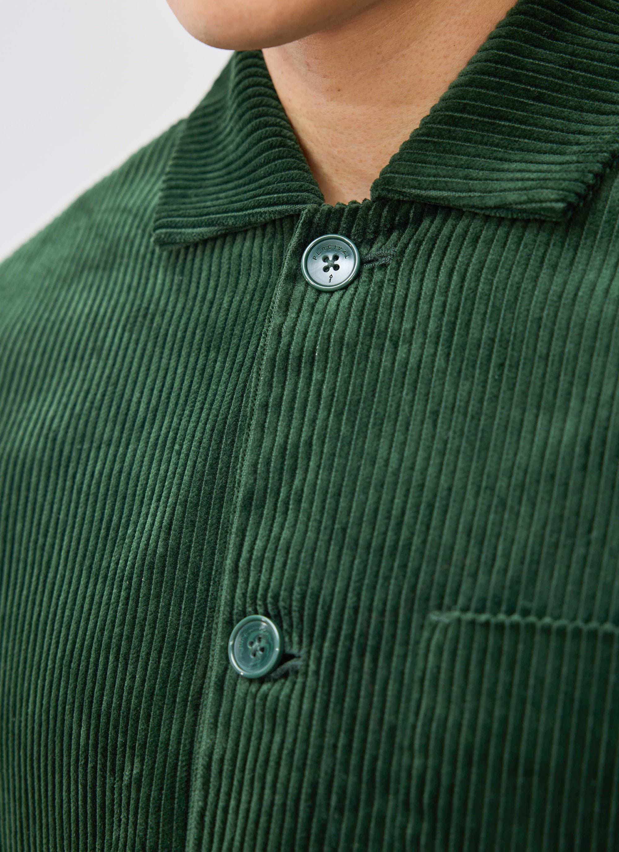 Close-up detail of the heavyweight cotton corduroy and branded button on the Percival Cord Overshirt in forest green.