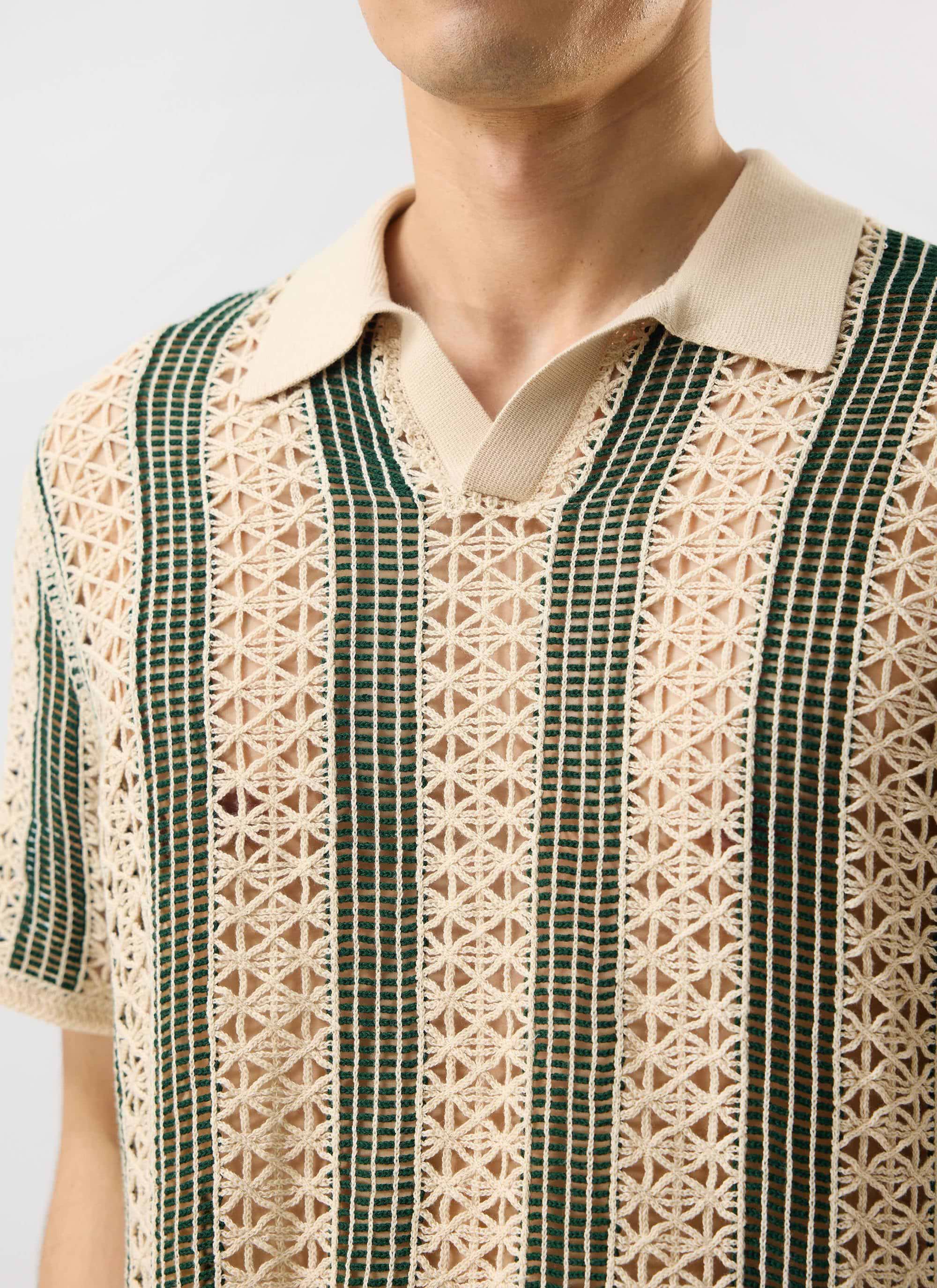 A close-up of the Percival Sarti Knitted Polo Shirt in ecru and forest green, showing the intricate crochet knit detail.