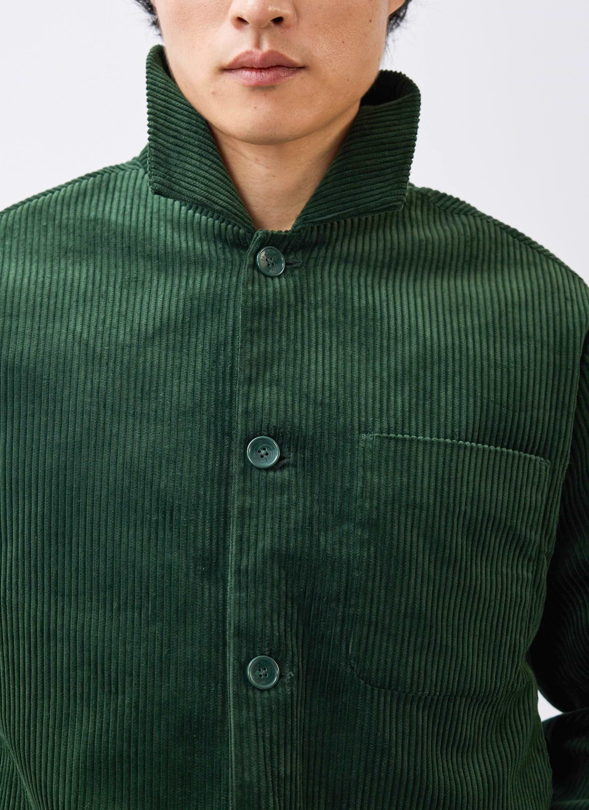 A close-up shot of a model wearing the Percival Cord Overshirt in forest green, focusing on the corduroy fabric and collar.