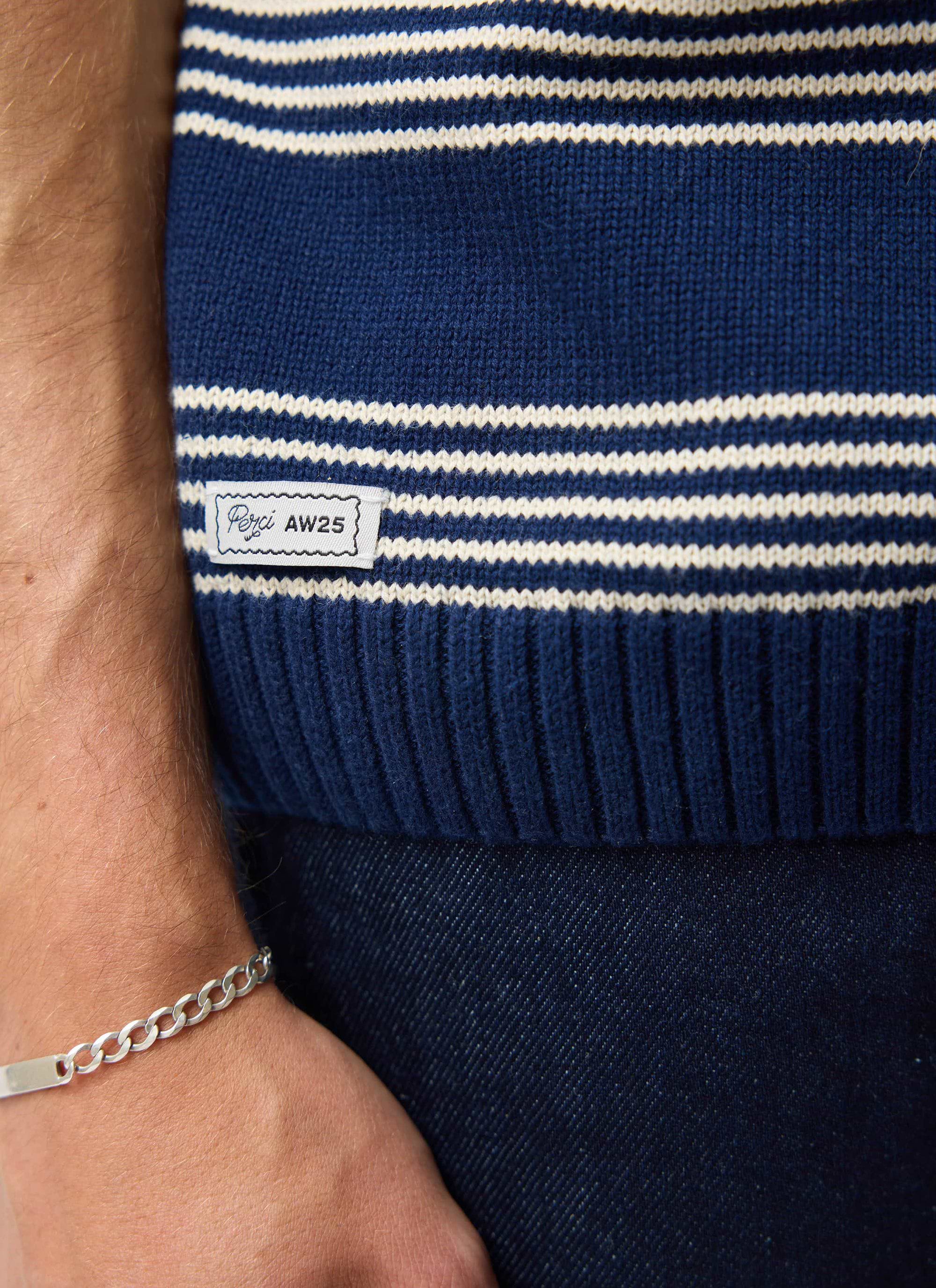 A close-up of the Percival Fiction Striped Knitted T-shirt in navy, showing the custom 'Perci AW25' label on the hem.
