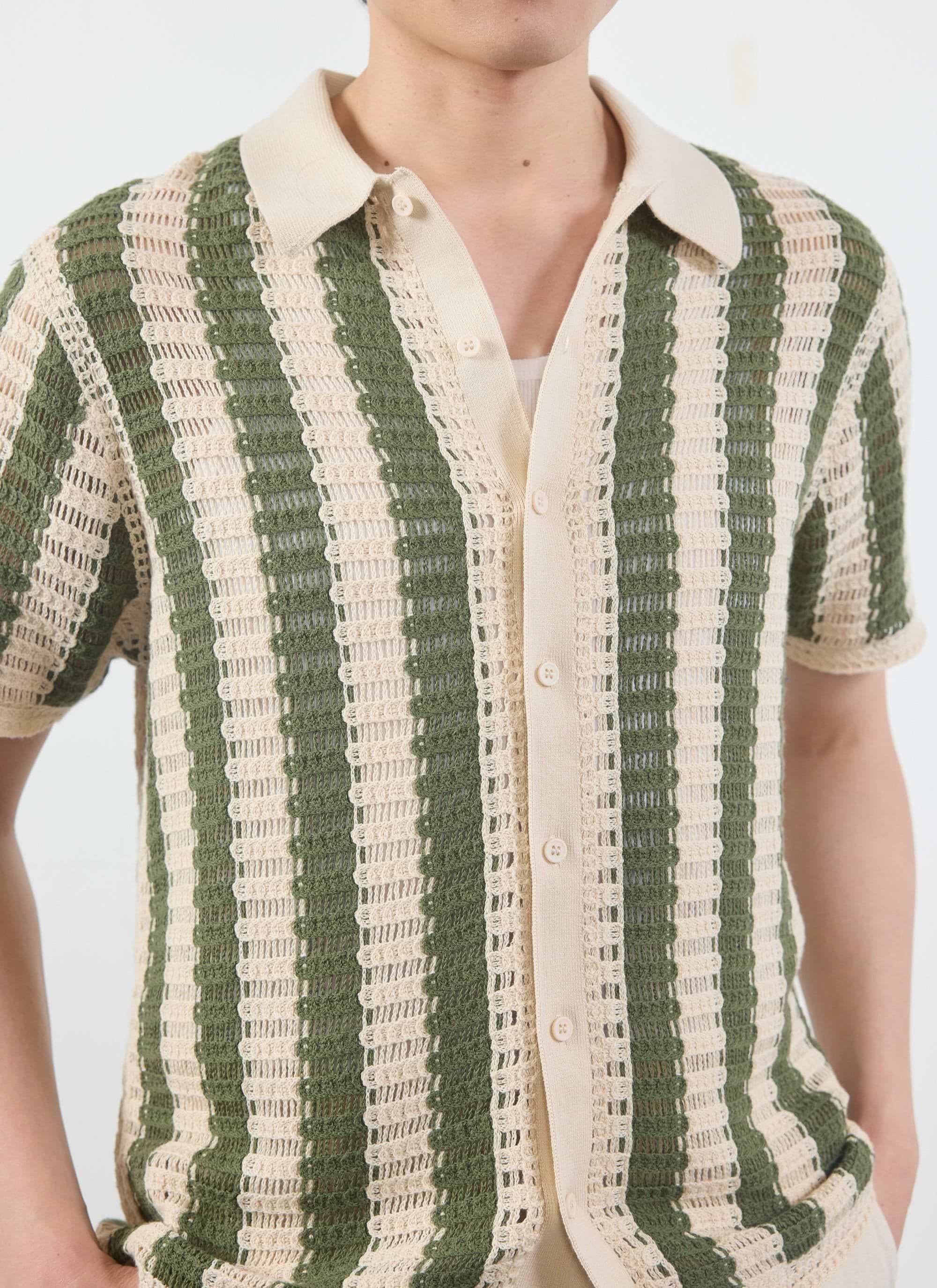 Close-up of a model wearing the Percival Barletta Knitted Shirt in olive, showing the cream and green crochet stripe detail.