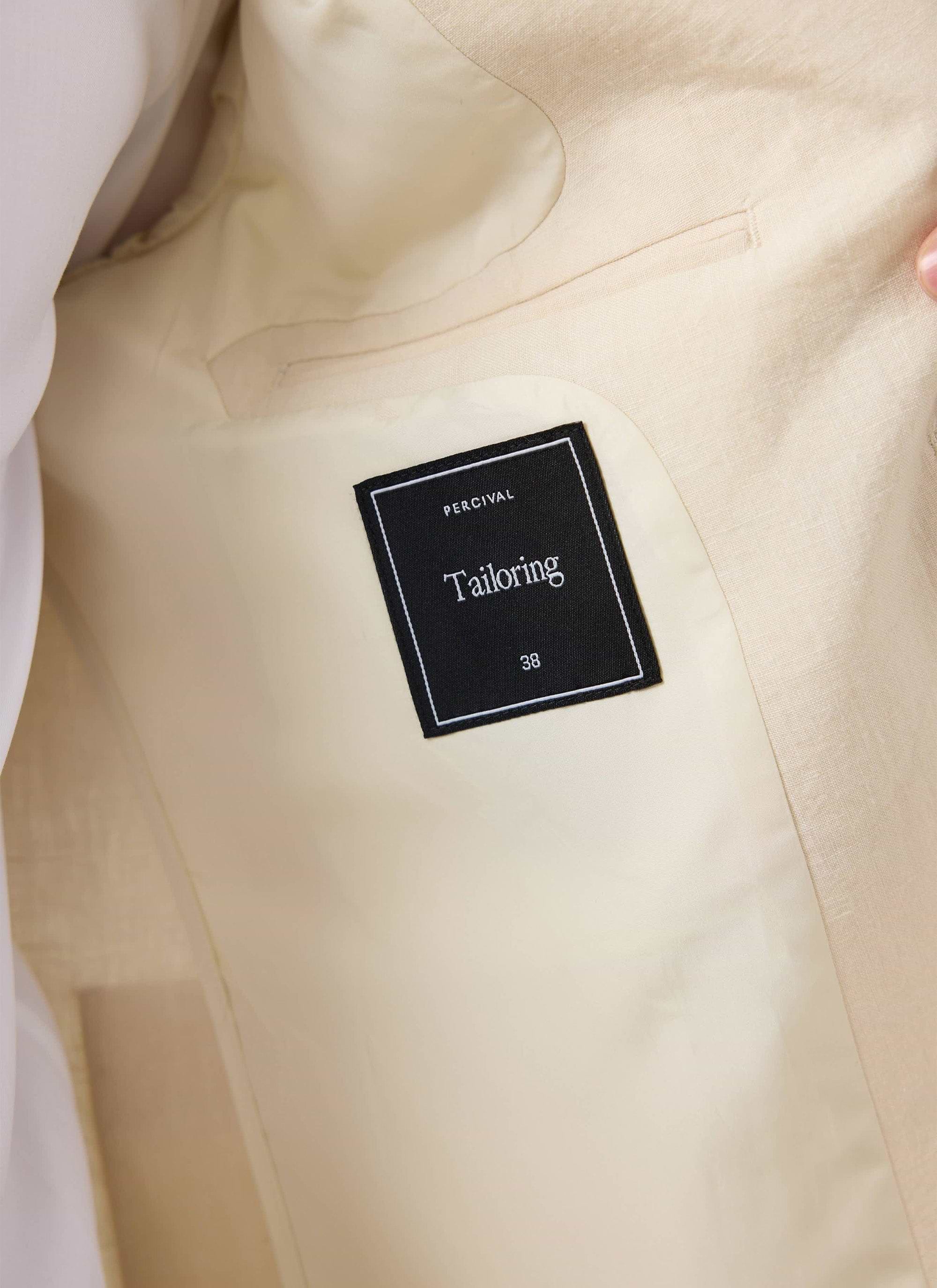 close up of the black Percival tailoring label inside the cream linen blazer