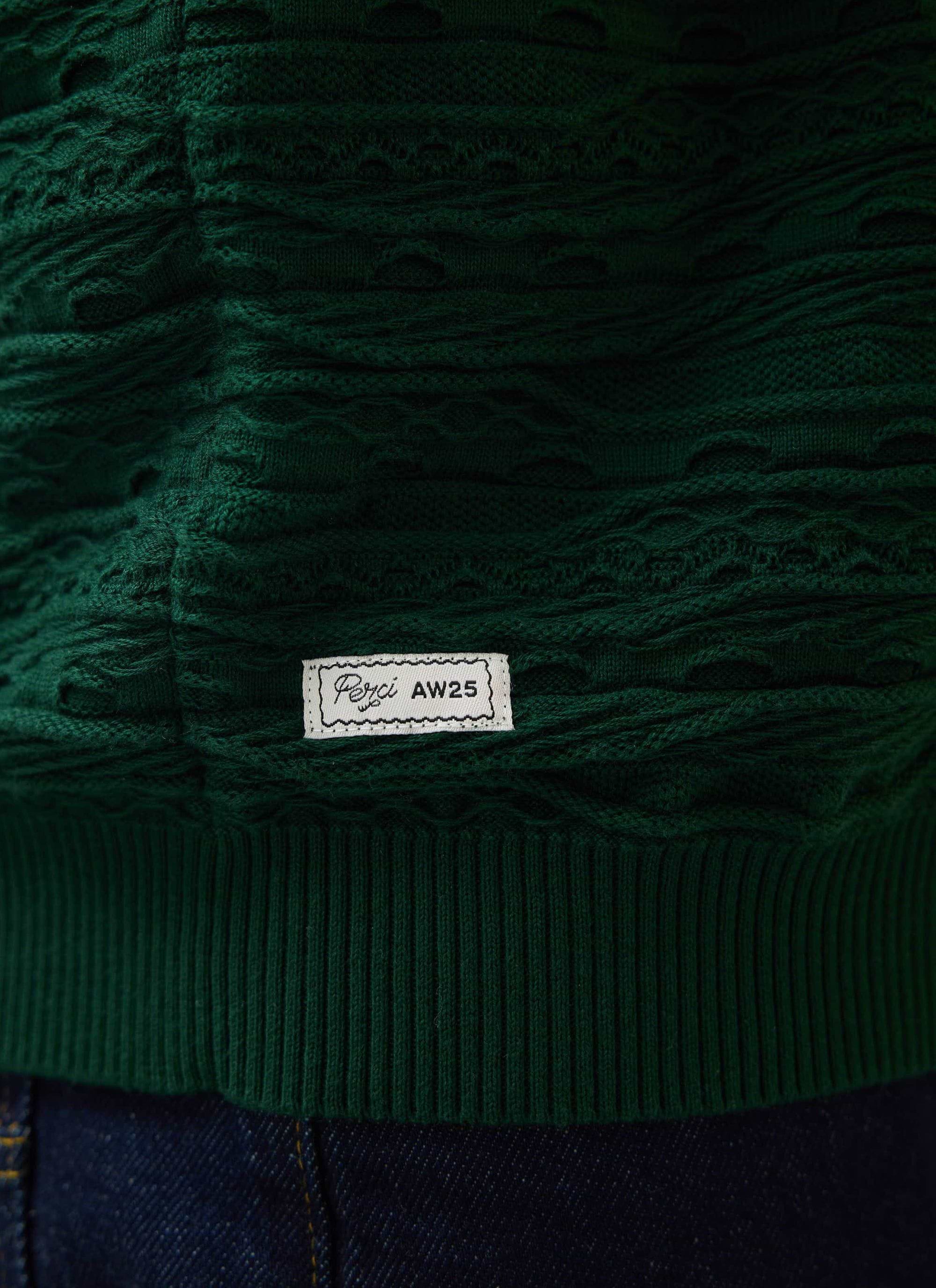 Close-up of the Percival Tales Knitted Jumper in forest green, showing the textural knit detail and AW25 label.