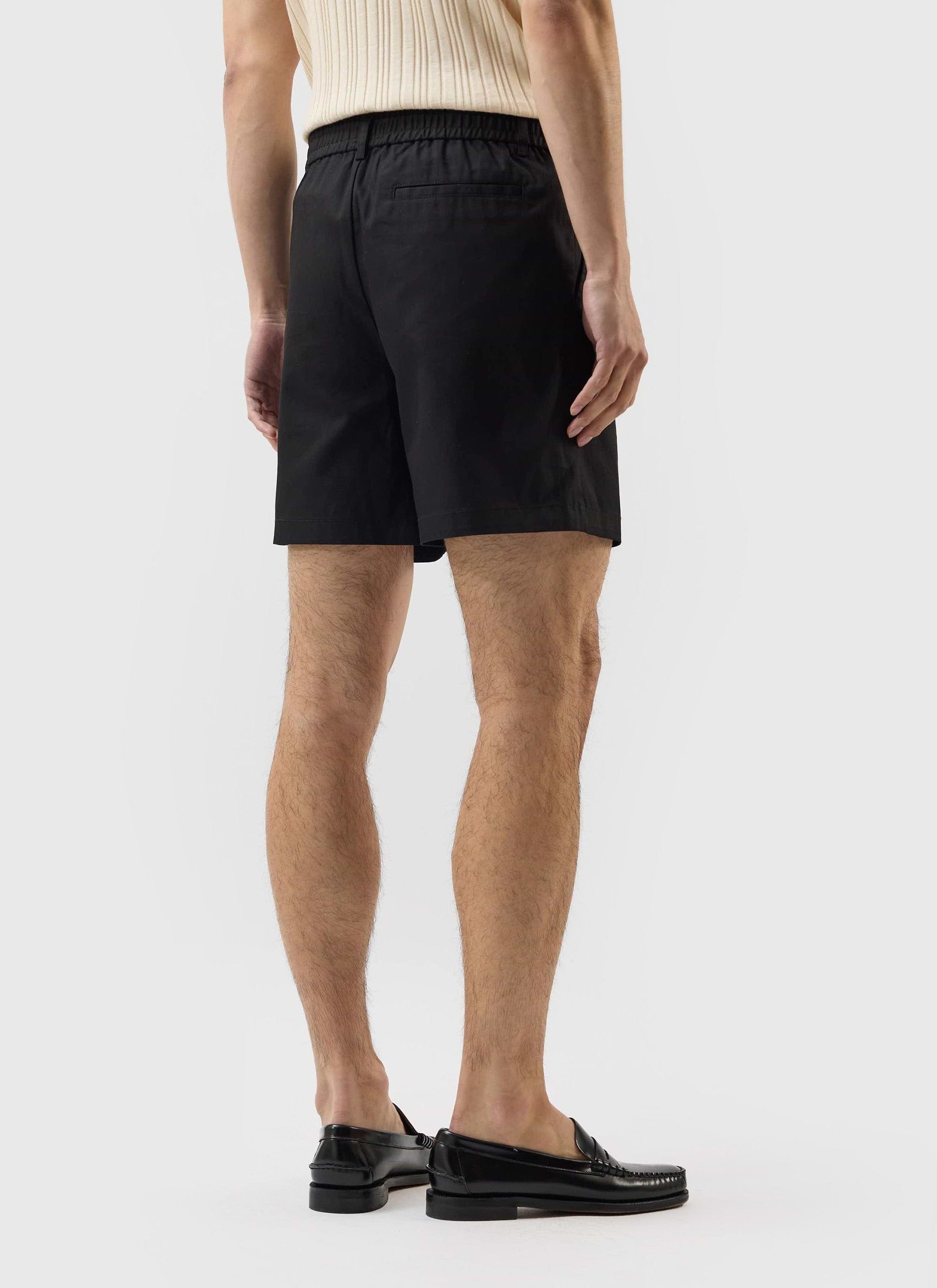 Rear view of a model wearing the black cotton Enzo Tailored Shorts from Percival, showing the fit and elasticated waistband.