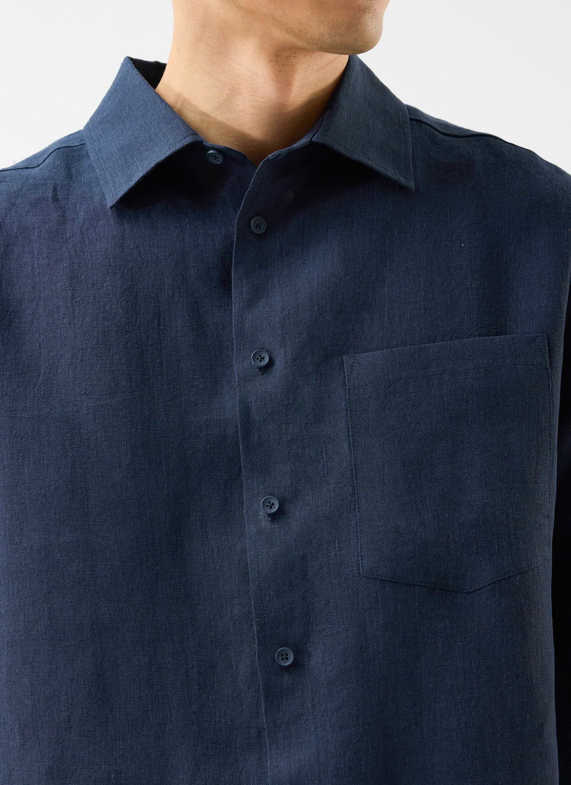 A close-up shot of a model wearing the Percival Pearce Shirt in navy linen, showing the collar and chest pocket detail.