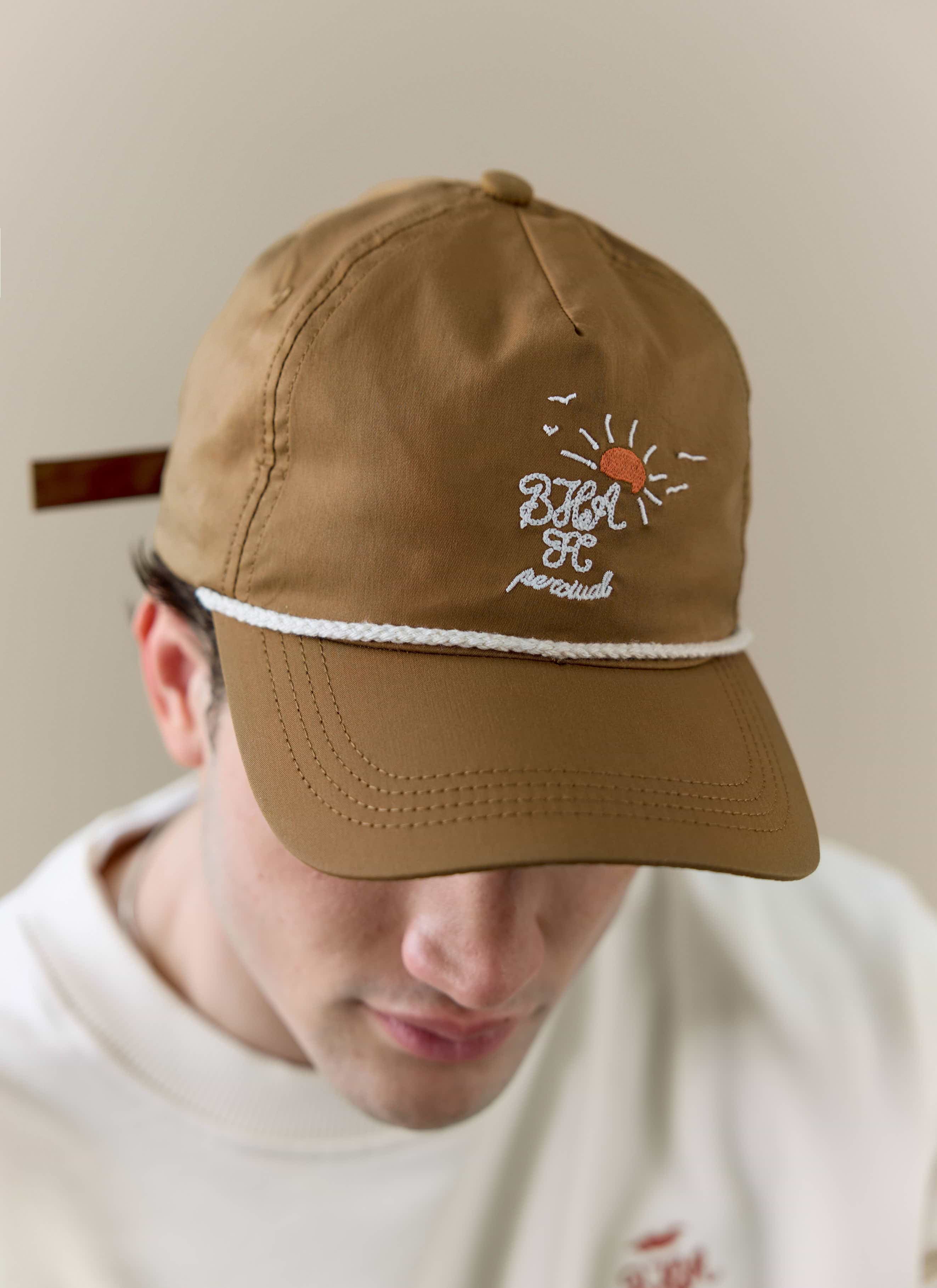 Close-up of a model wearing the rust Percival x Brighton & Hove Albion F.C. trucker cap, showing the detailed embroidery.