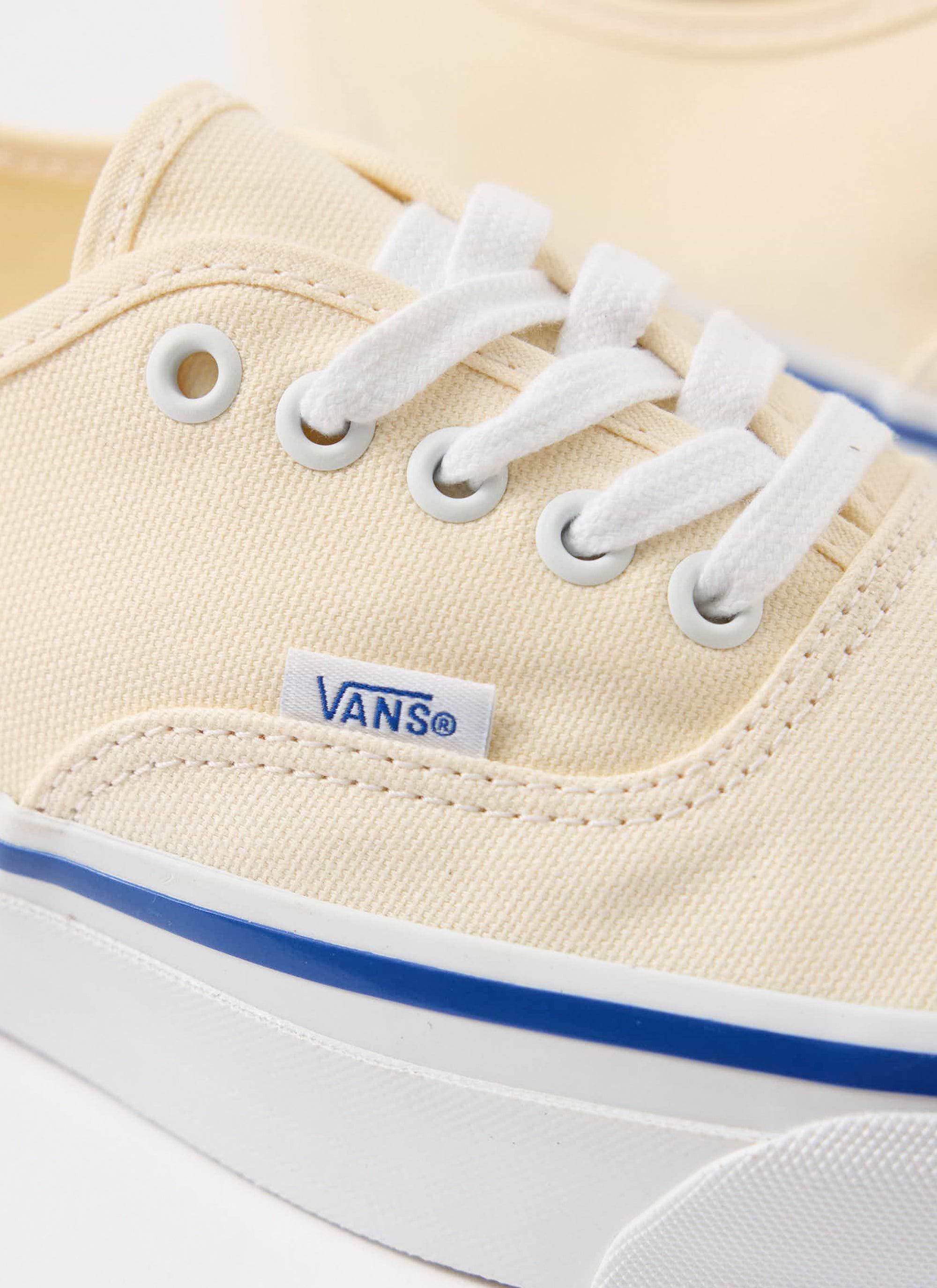 A close-up of the off-white canvas Vans Authentic 44 shoes, showing the side logo tag and white laces, from Percival.