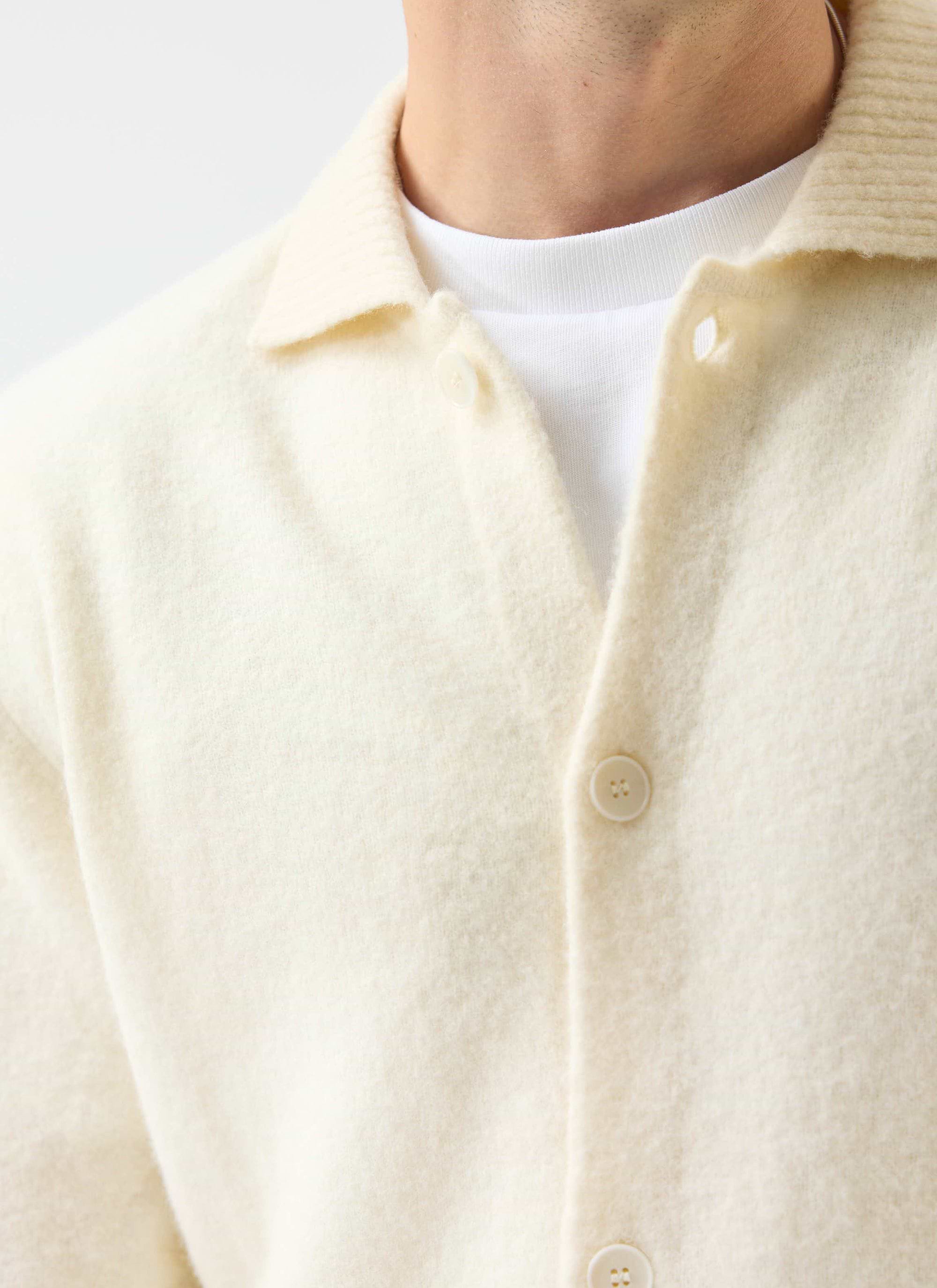 A close-up of a model wearing the Percival Archive Wool Collared Cardigan in ecru cream over a white t-shirt.