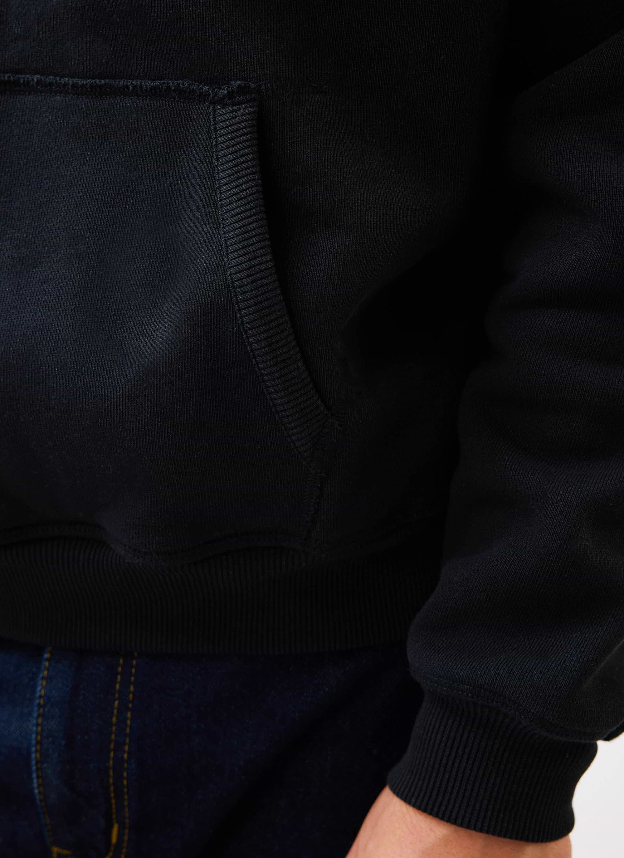 A close-up of the Percival Heritage 90's Raglan Hoodie in black, showing the kangaroo pocket and ribbed cuff detail.