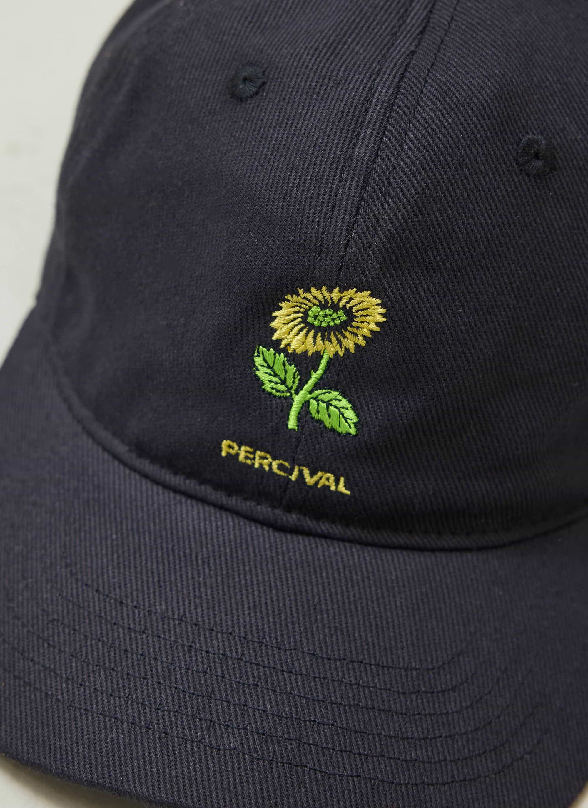 A close-up of the yellow flower and logo embroidery on the black cotton Percival Nature Reserve Cap.