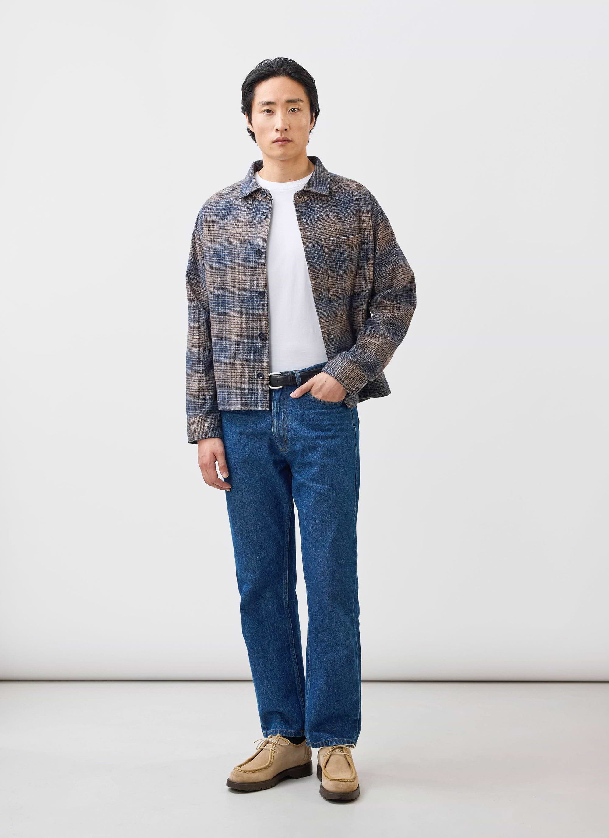 A model wears the Percival Luton Check Overshirt in brown over a white t-shirt and blue jeans against a white background.