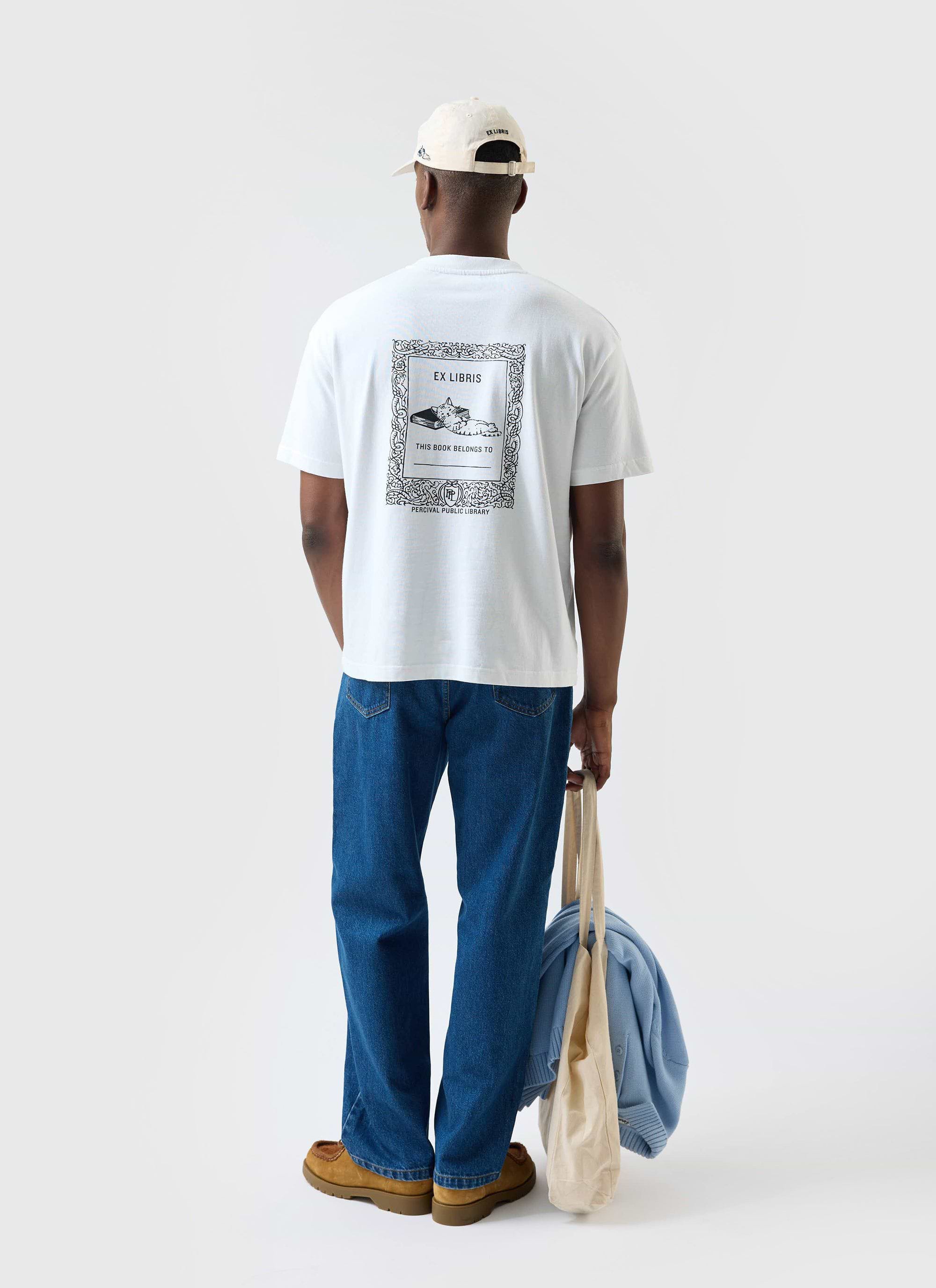 A model seen from behind wearing the white Percival Ex Libris oversized t-shirt, showing the back graphic print.