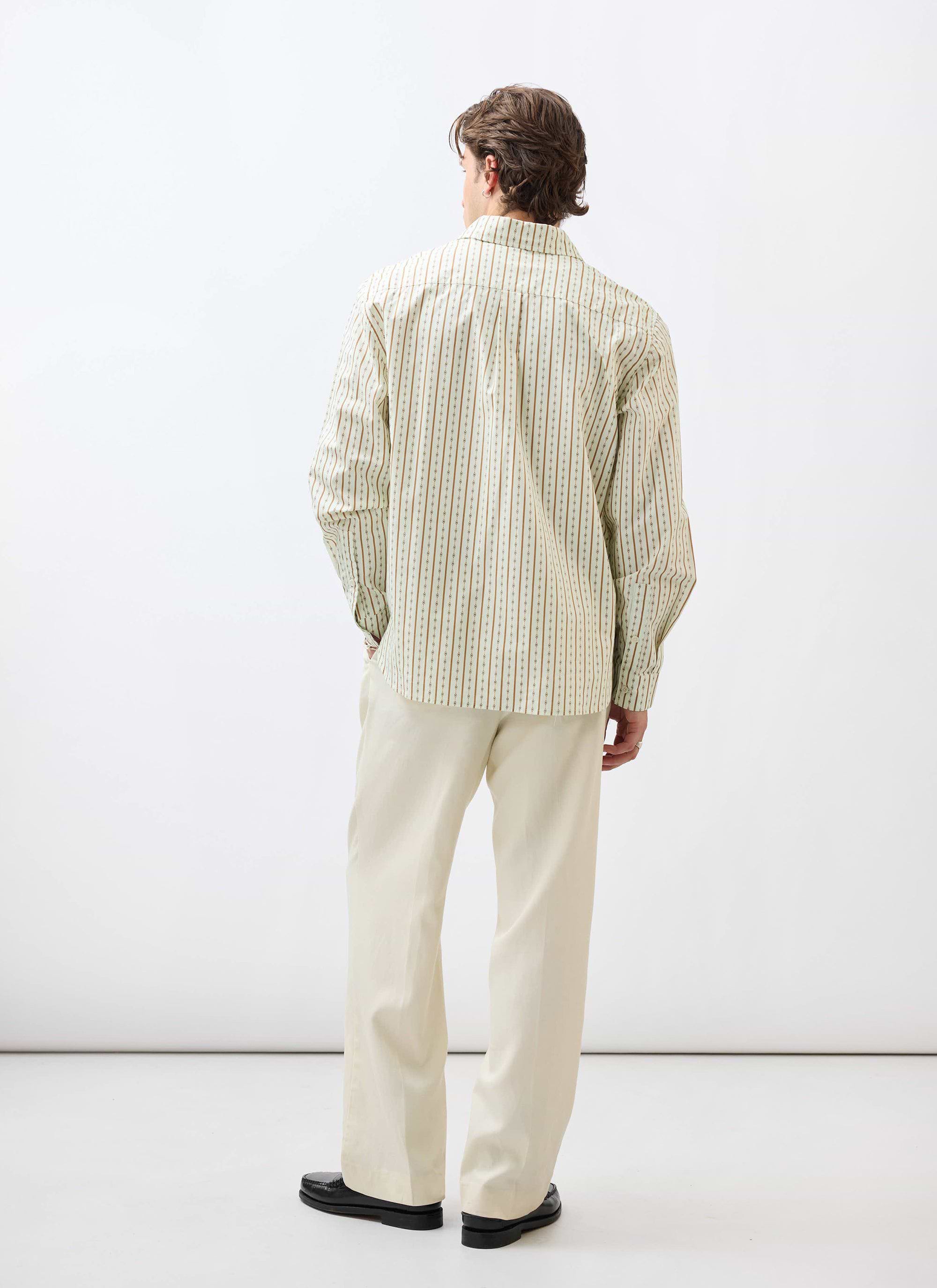 A male model, seen from the back, wears the Percival Binding Oversized Pearce Shirt in ecru with smart ecru trousers.