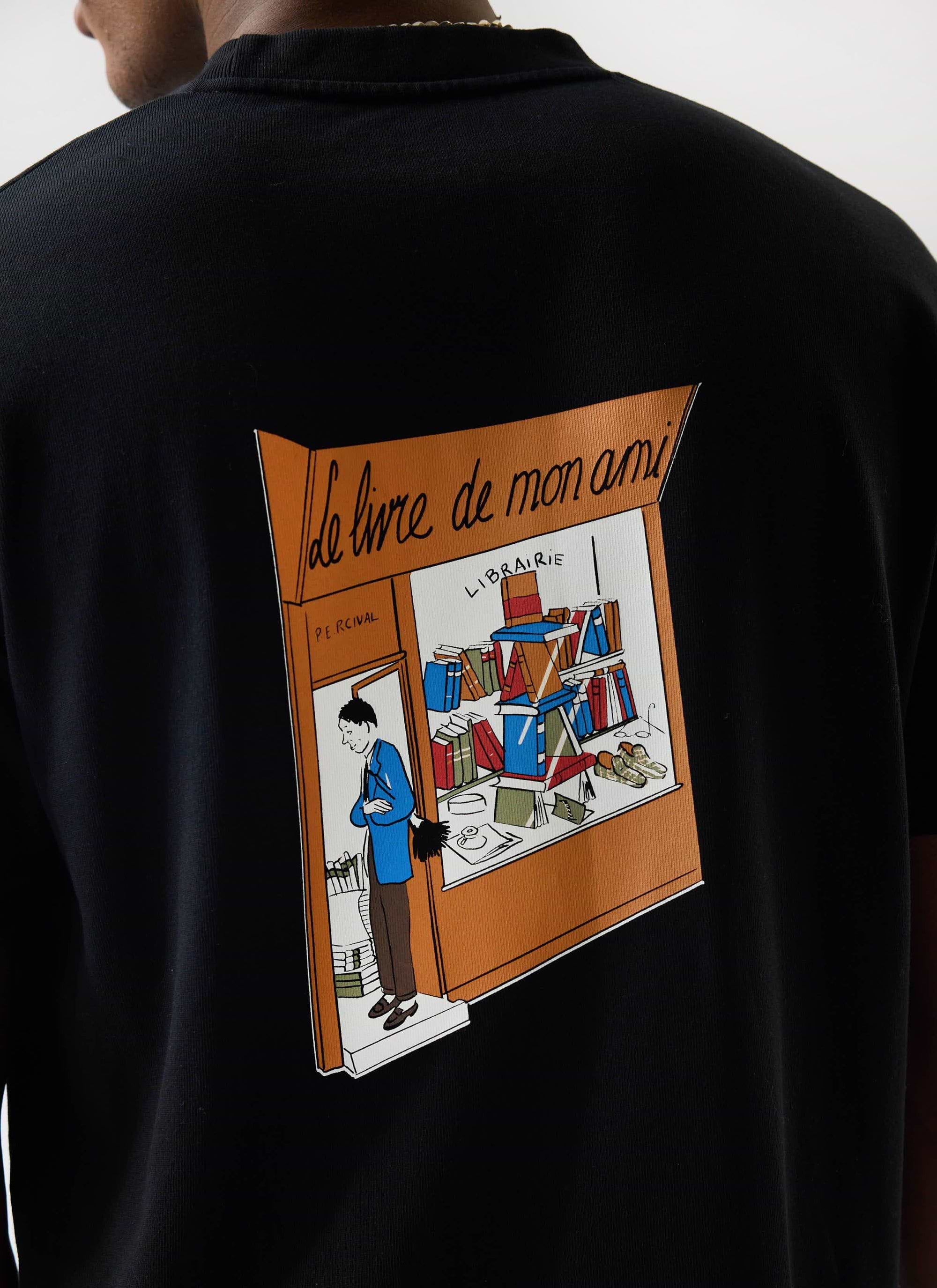 A close-up of the 'Le Livre De Mon Ami' graphic print on the back of the oversized black cotton t-shirt by Percival.