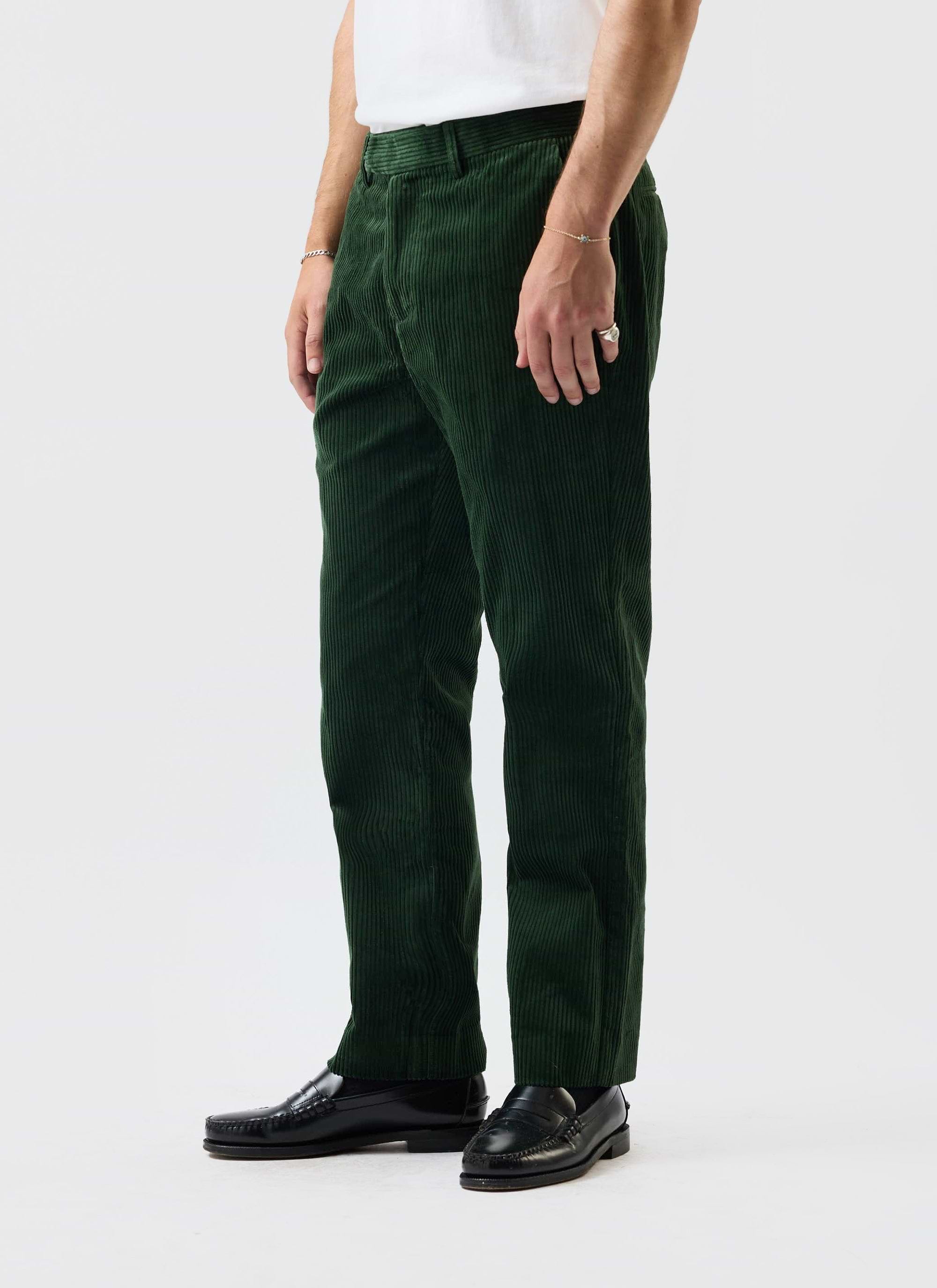 A model wears the Percival Tailored Chunky Cord Trousers in Forest, styled with a white tee and black loafers.
