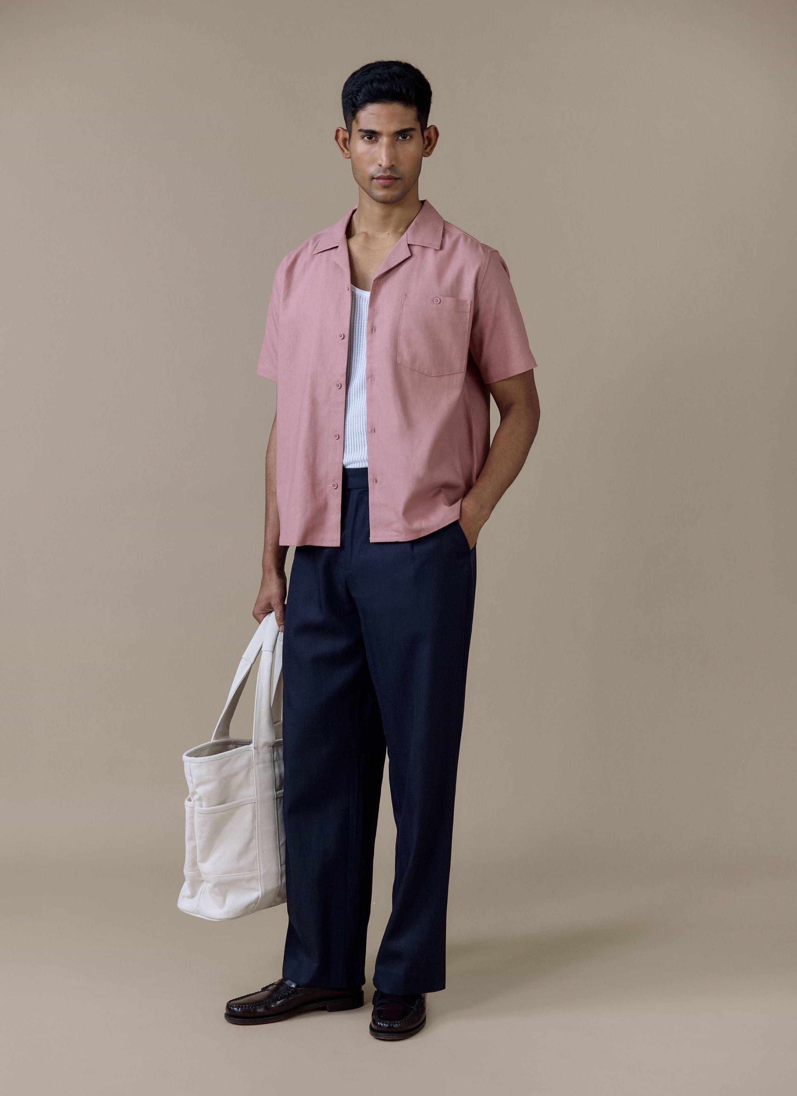 Percival Short Sleeve Cuban Shirt in dusty pink linen, worn with navy pleated trousers and a white canvas tote bag.