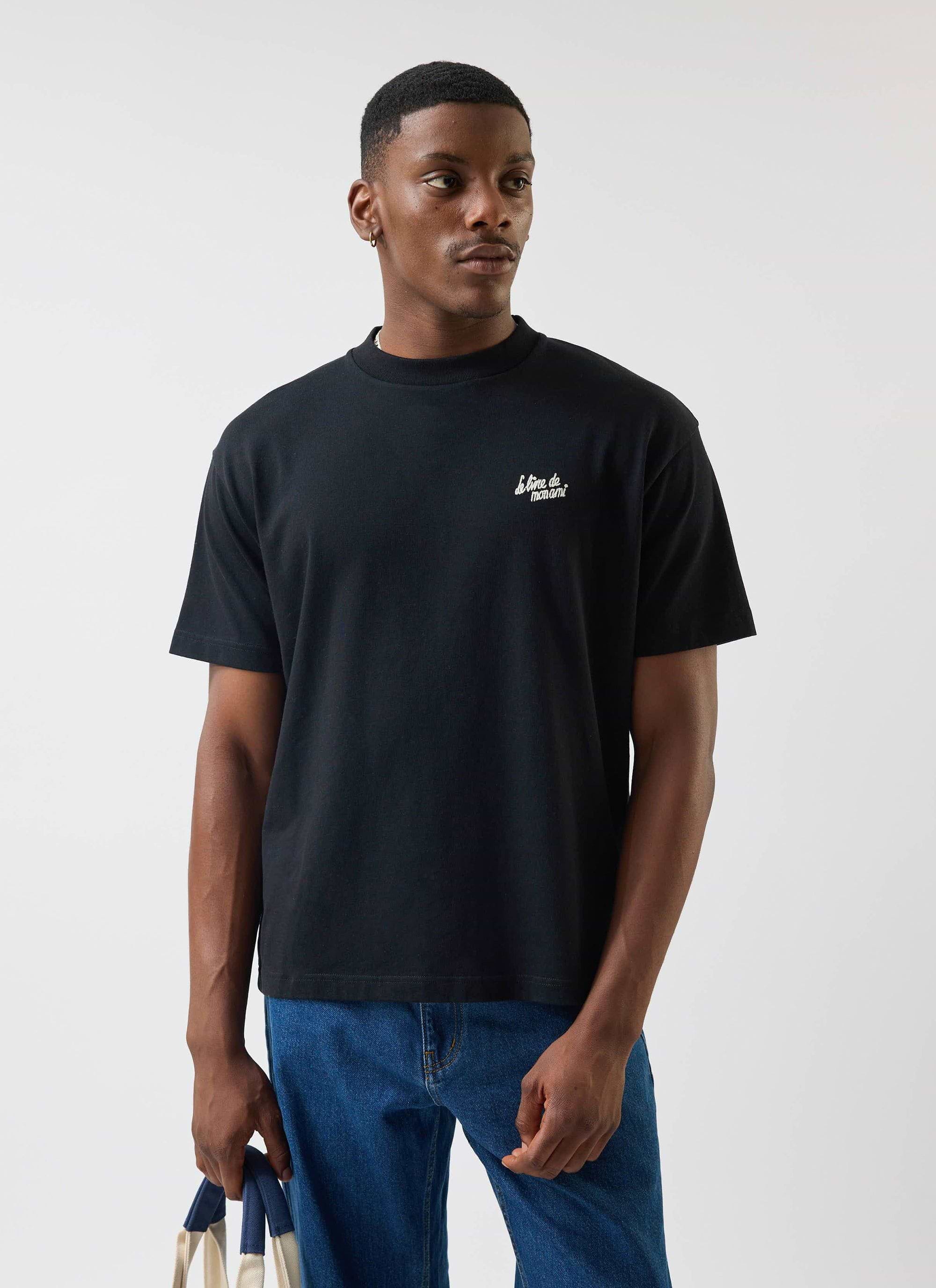 Front view of a model wearing the Percival Le Livre De Mon Ami oversized t-shirt in black, paired with blue jeans.