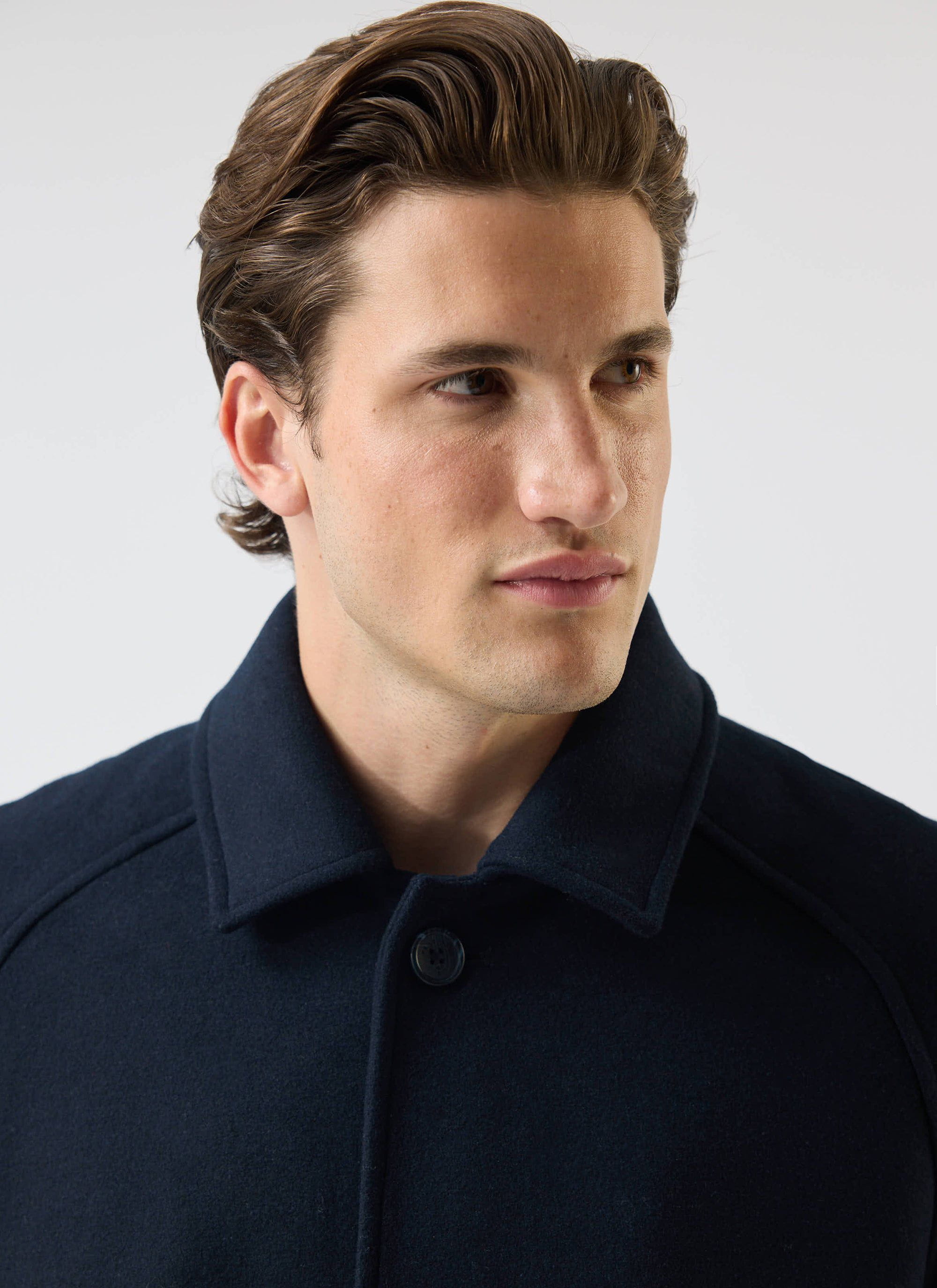 A close-up shot of a model wearing the navy Wool Car Coat from Percival, showing the collar and fabric texture.