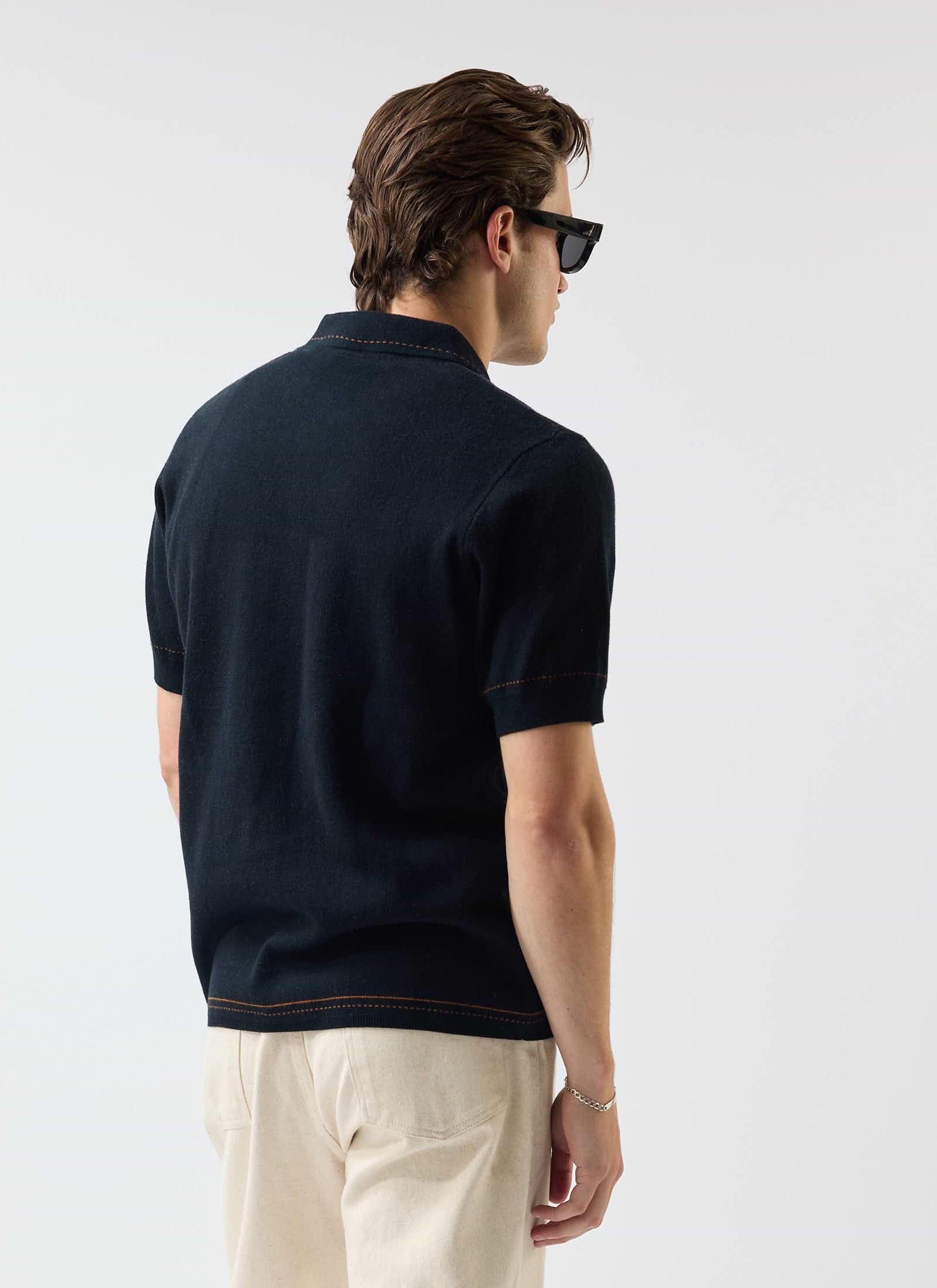A model, seen from behind, wears the Percival Folio Knitted Shirt in dark navy with tobacco stitching detail.
