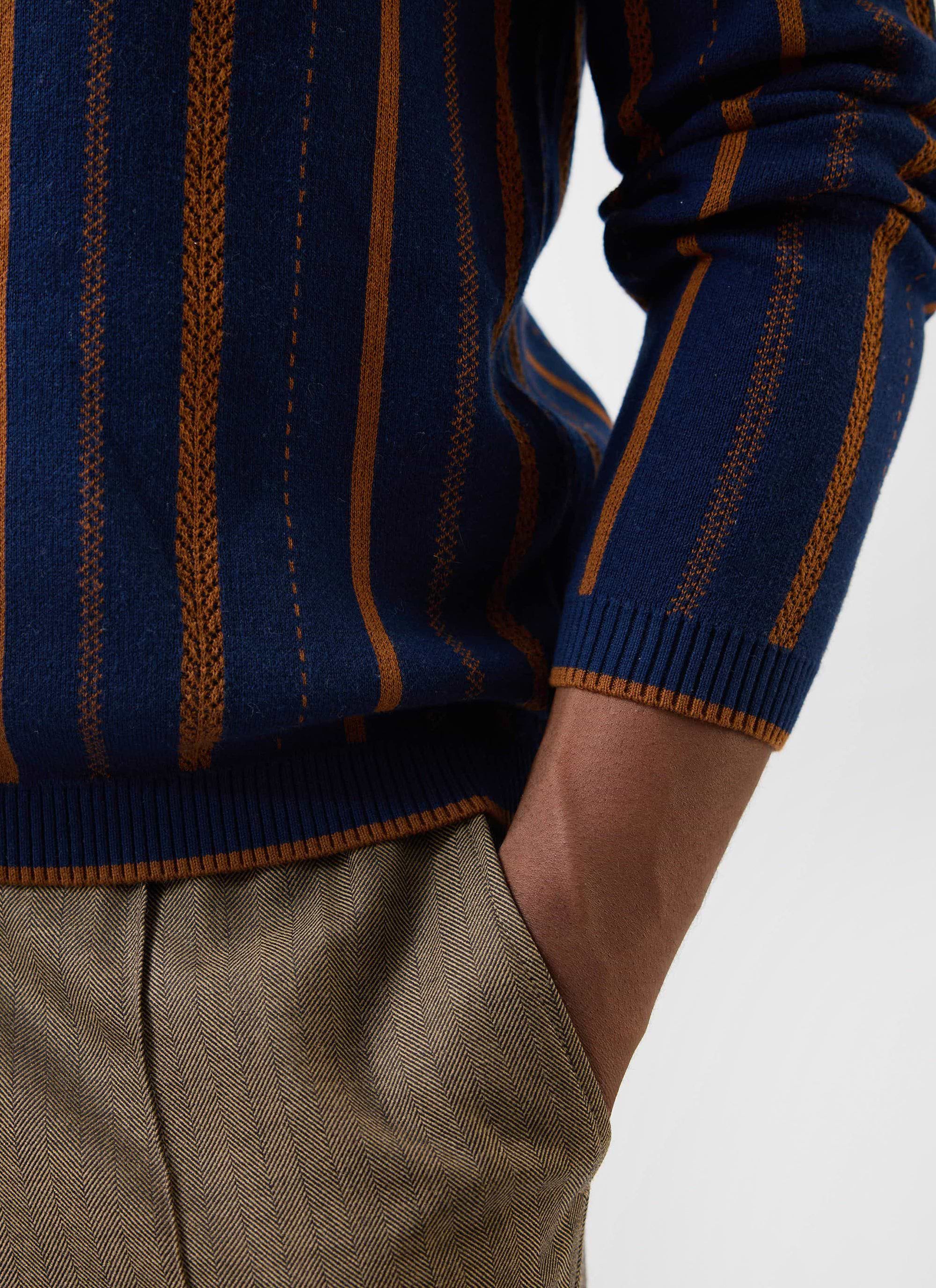 A close-up of a model wearing the navy Percival Citation Knitted Football Shirt, showing the striped texture and ribbed cuff.