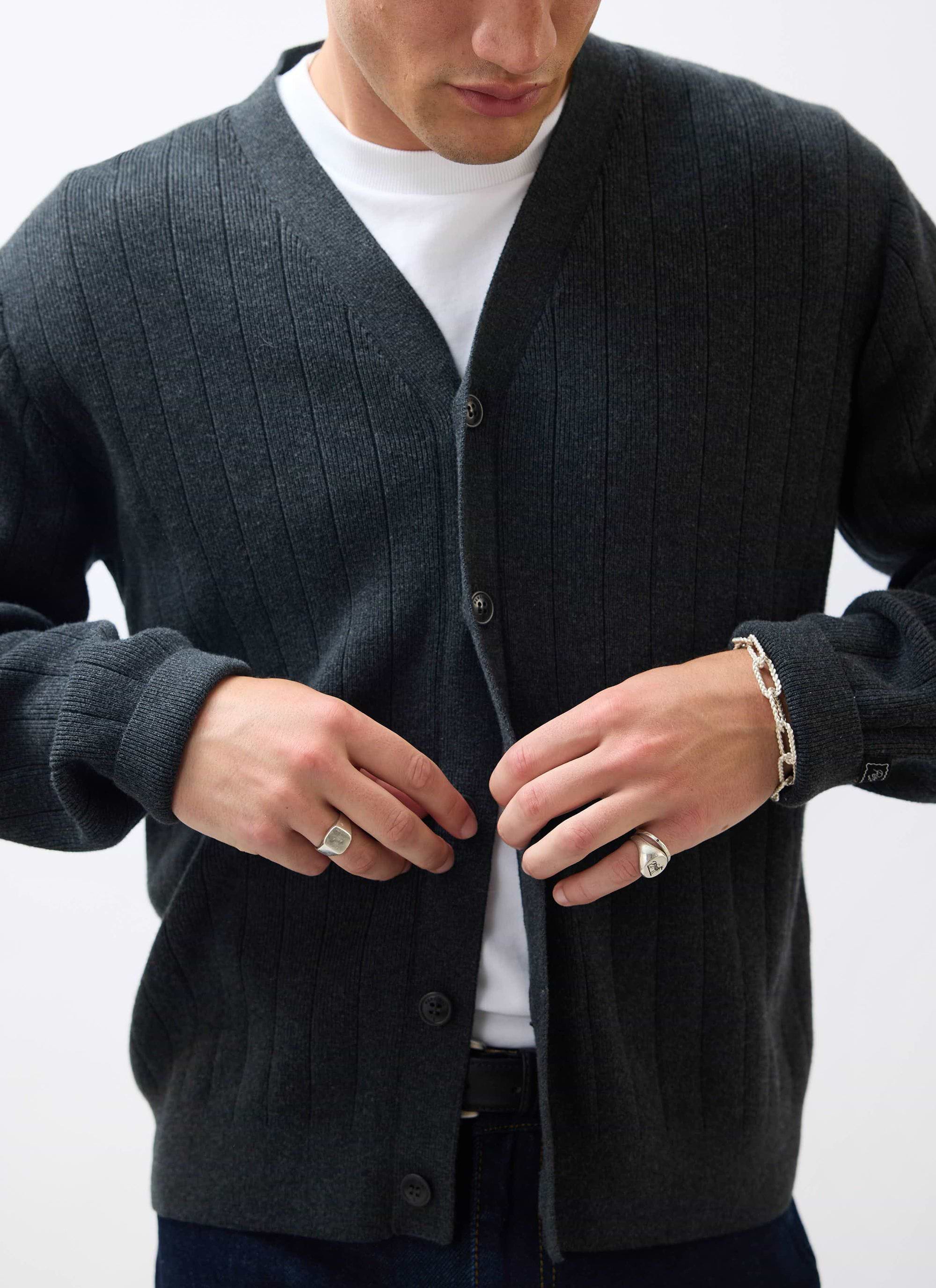 A close-up of a man buttoning the grey ribbed-knit Editor Cardigan from Percival over a white t-shirt.
