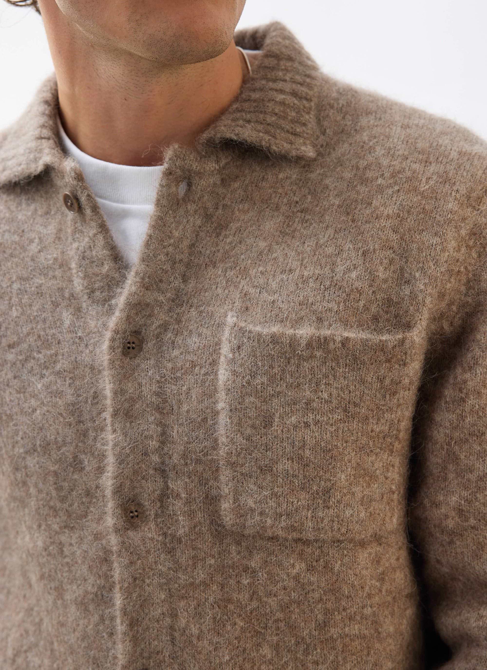 Close up of a model wearing the Percival Novel Collared Cardigan in Oak, showing its textured wool fabric and chest pocket.