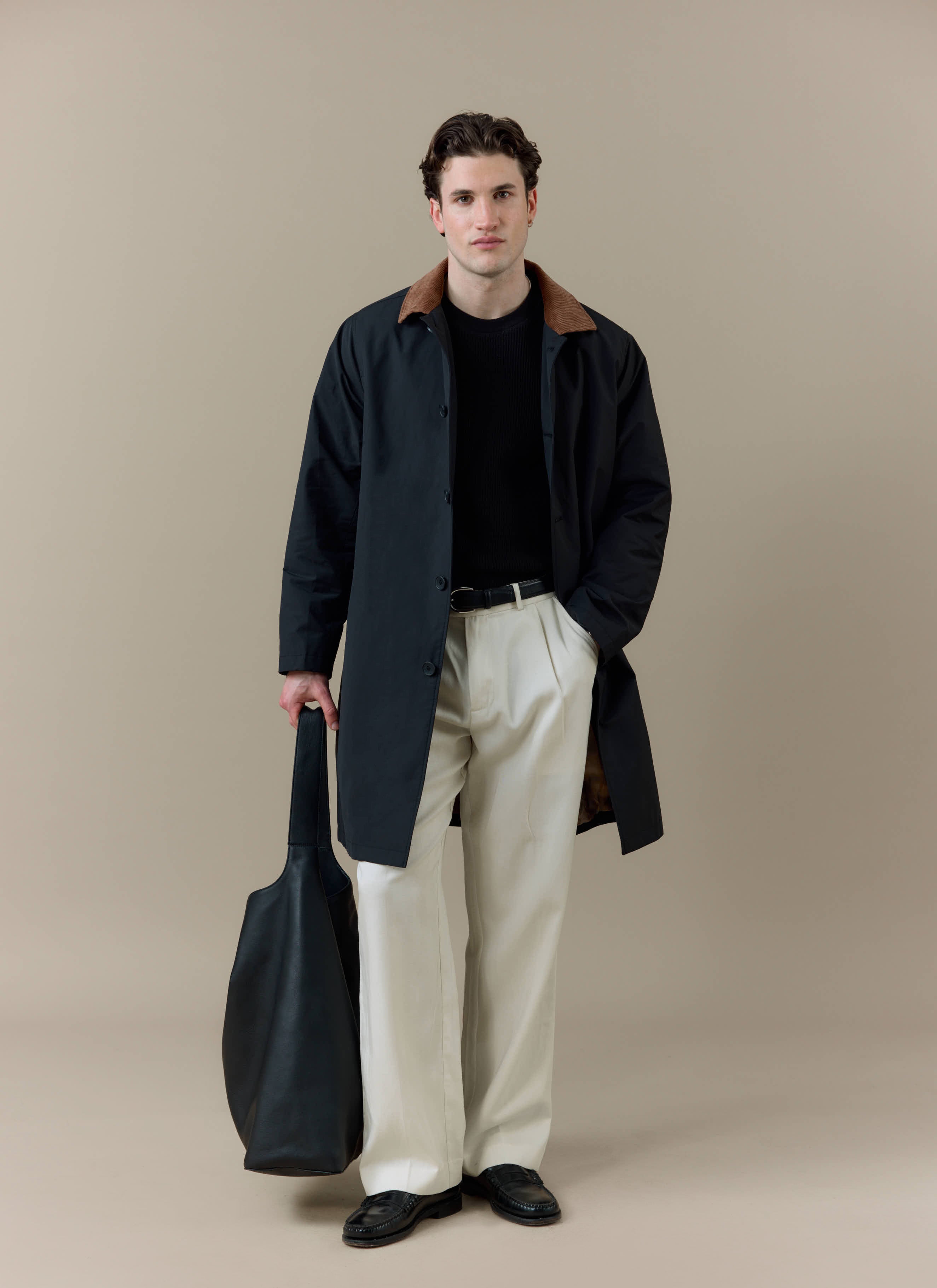 A model wearing the black Percival Cord Collar Relaxed Trench Coat featuring a contrast brown corduroy collar.