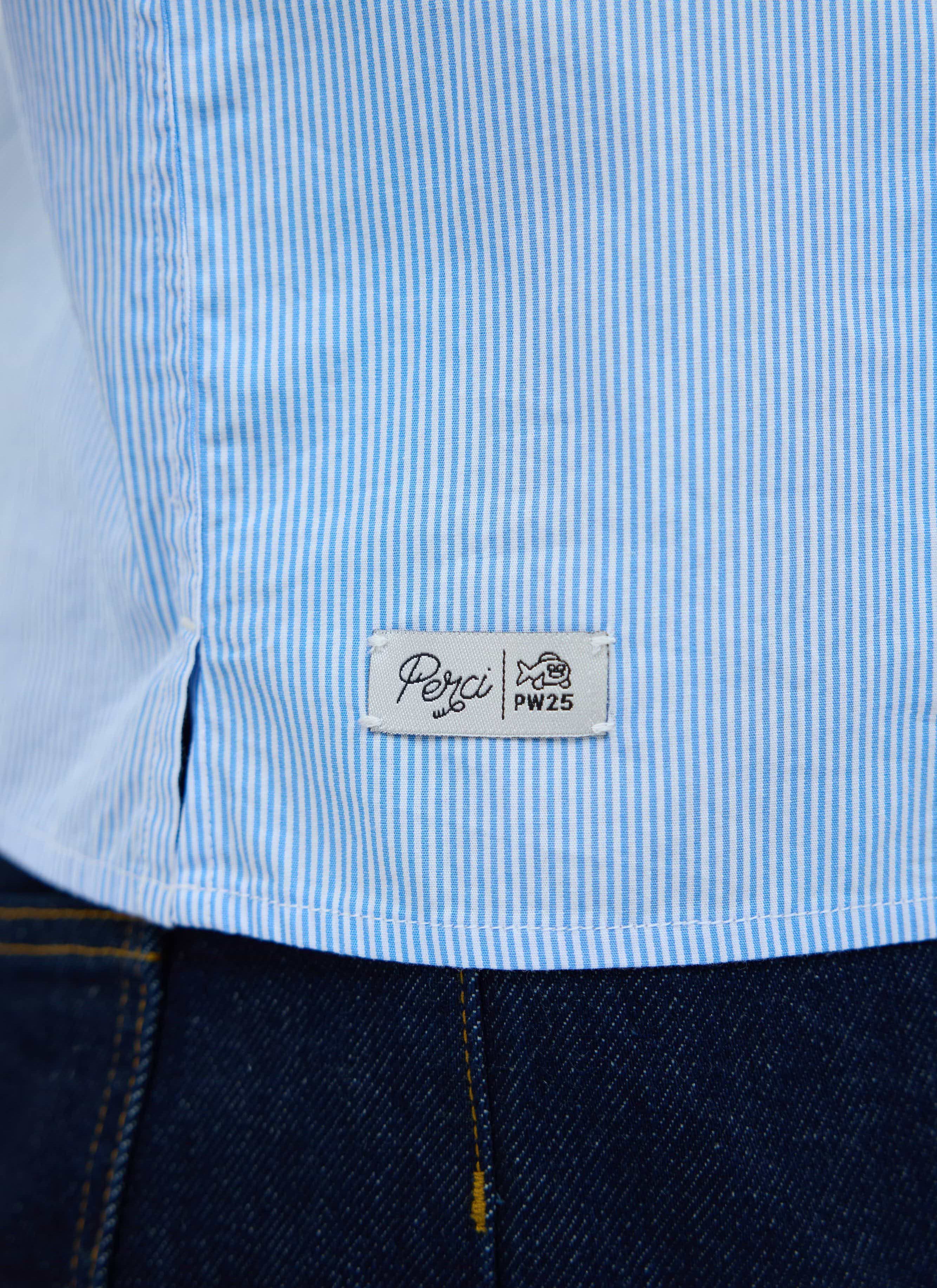 A close-up shot of the woven Percival label on the hem of the blue and white striped Sunflower Shirt.
