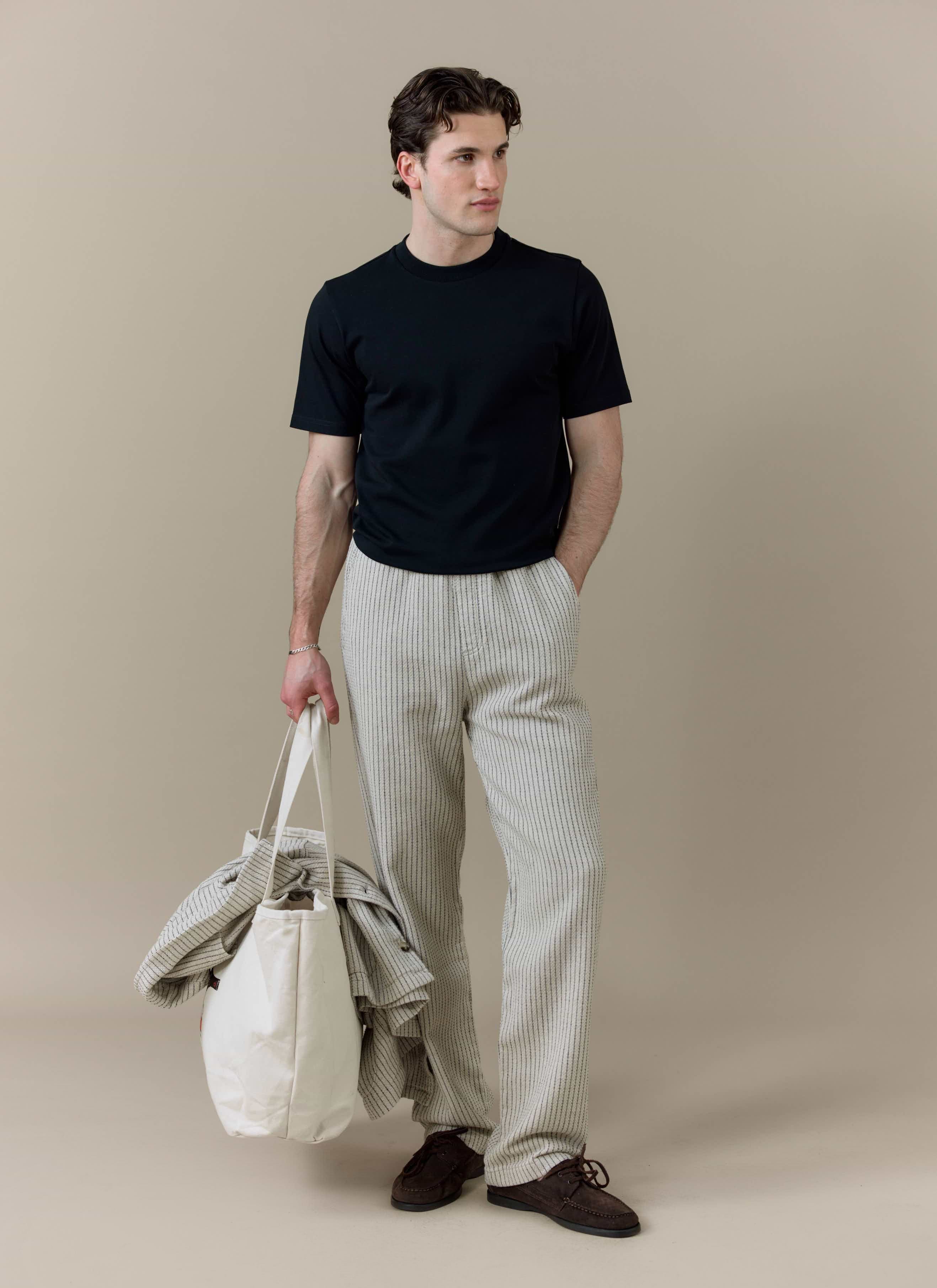 A model wearing the Percival Sorrento Wide Leg Trouser in cream linen, featuring a relaxed, straight leg fit.