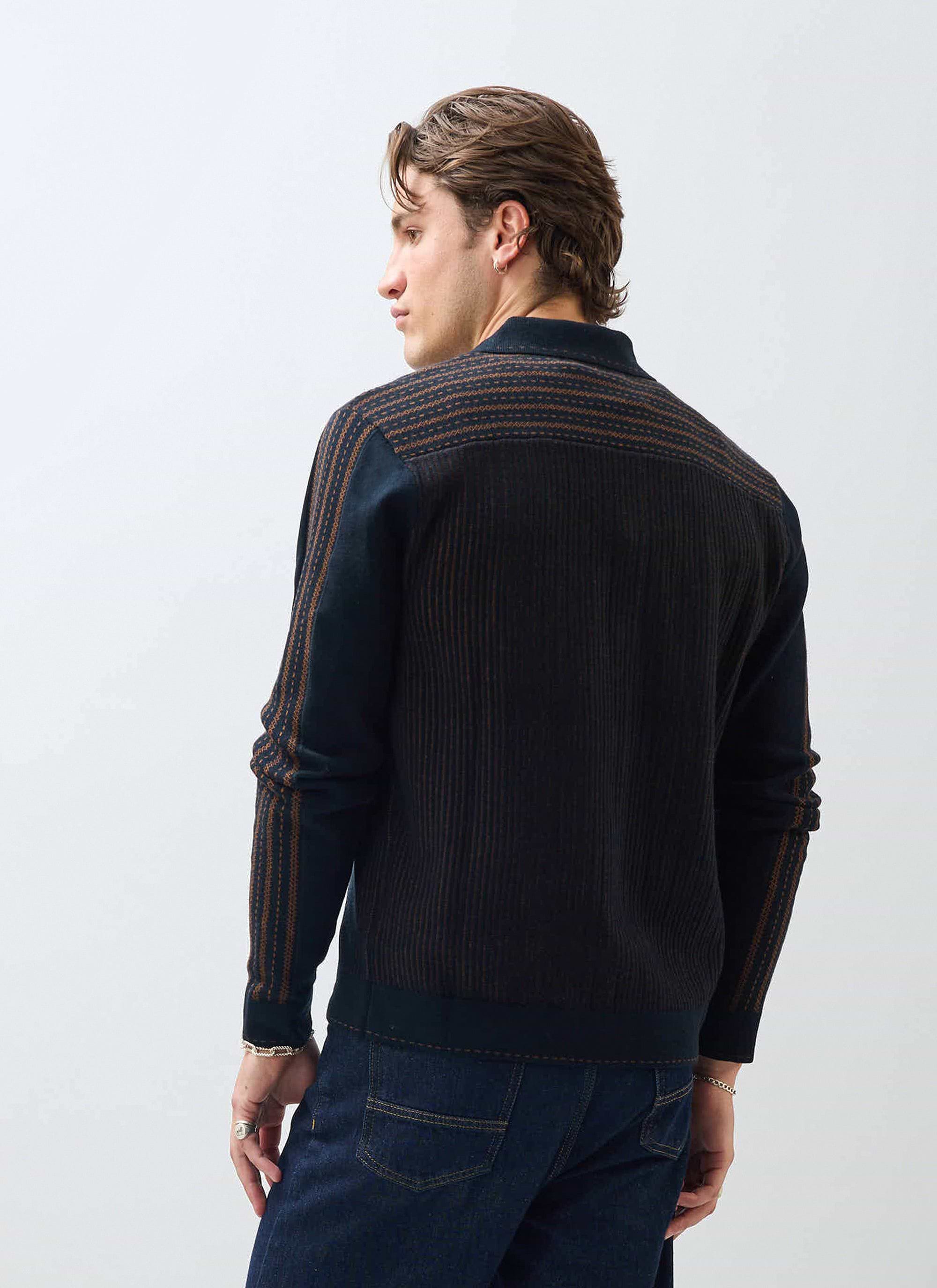 A model wears the Percival Appendix Long Sleeve Knitted Shirt in black, showing the brown jacquard detailing on the back.