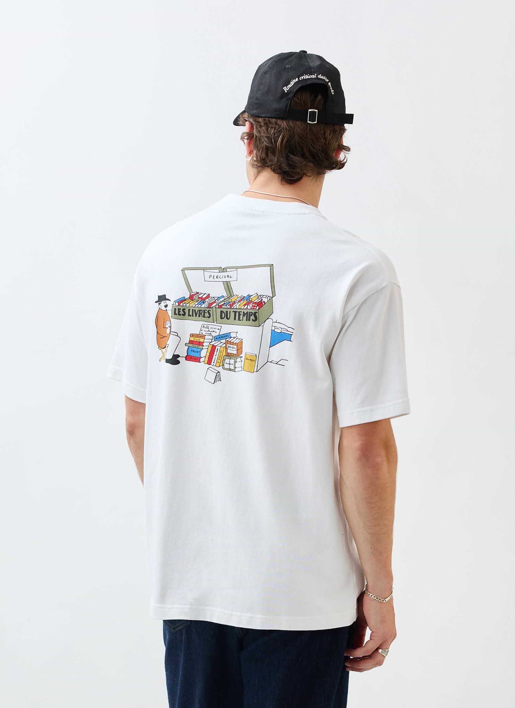 A model wears the white Percival Du Temps t-shirt, seen from behind to showcase the colourful 'Les Livres Du Temps' graphic.
