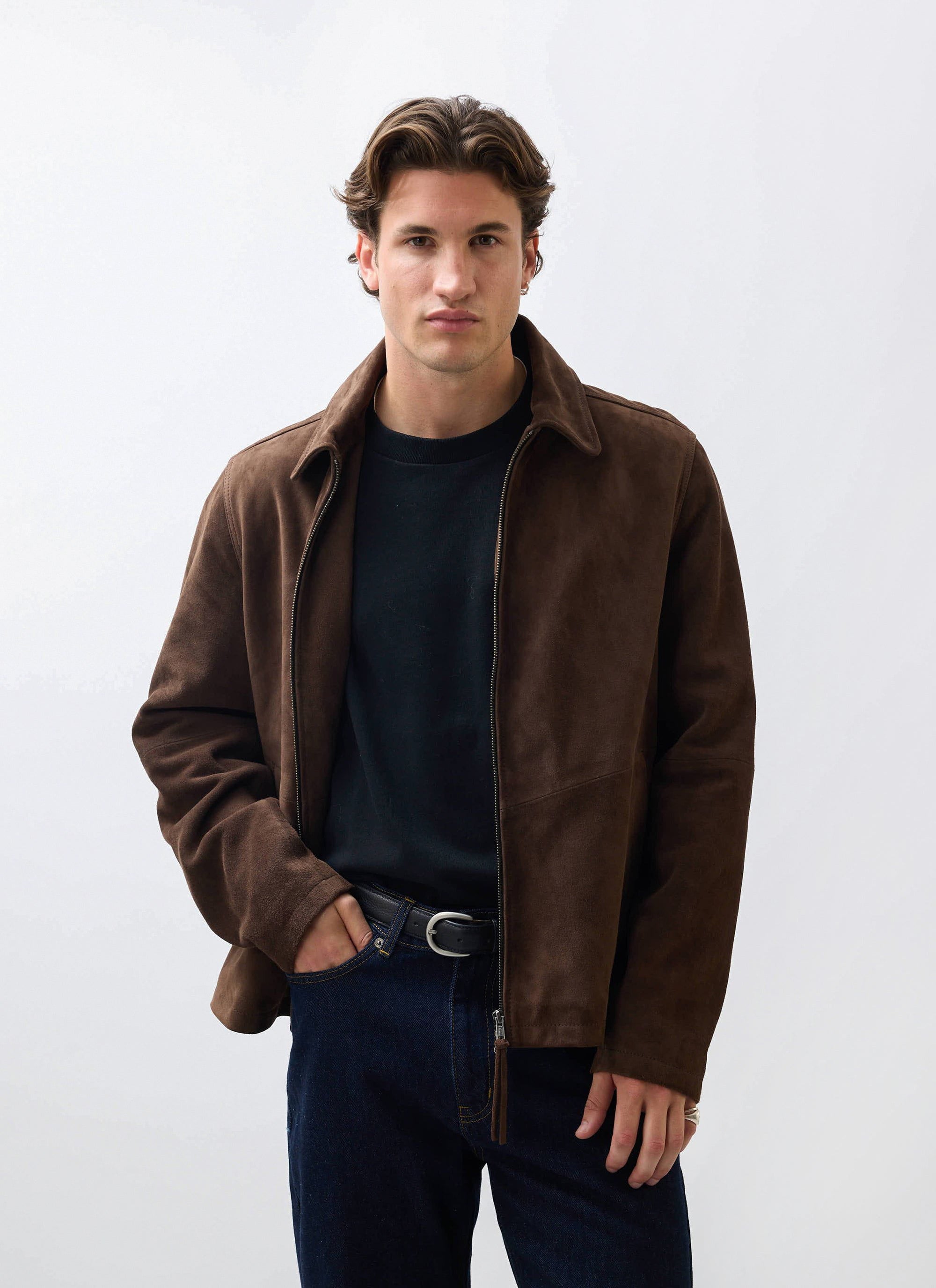 A model wears the Percival Prologue Soft Suede Jacket in espresso brown, styled with a black t-shirt and dark jeans.