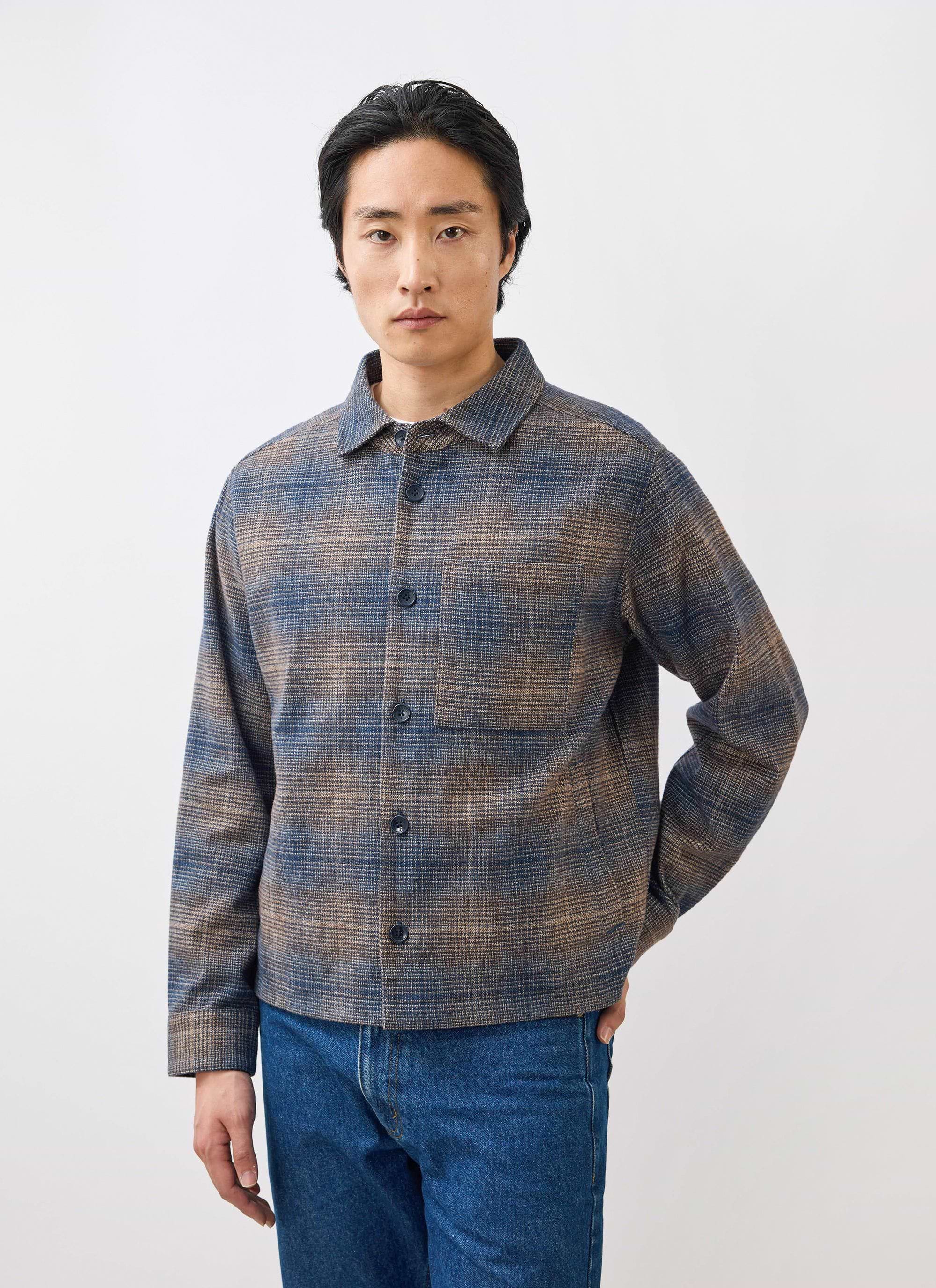 A man models the Percival Luton Check Overshirt in brown, a brushed cotton jacket, against a clean white studio background.
