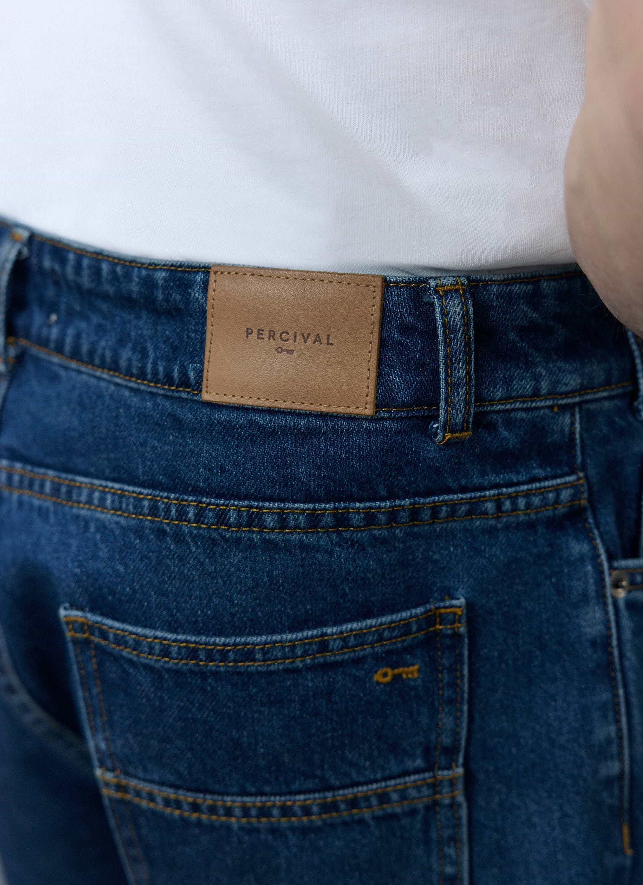 A close-up of the brown leather logo patch on the back of the Percival Wide Leg Denim Jeans in mid wash blue.